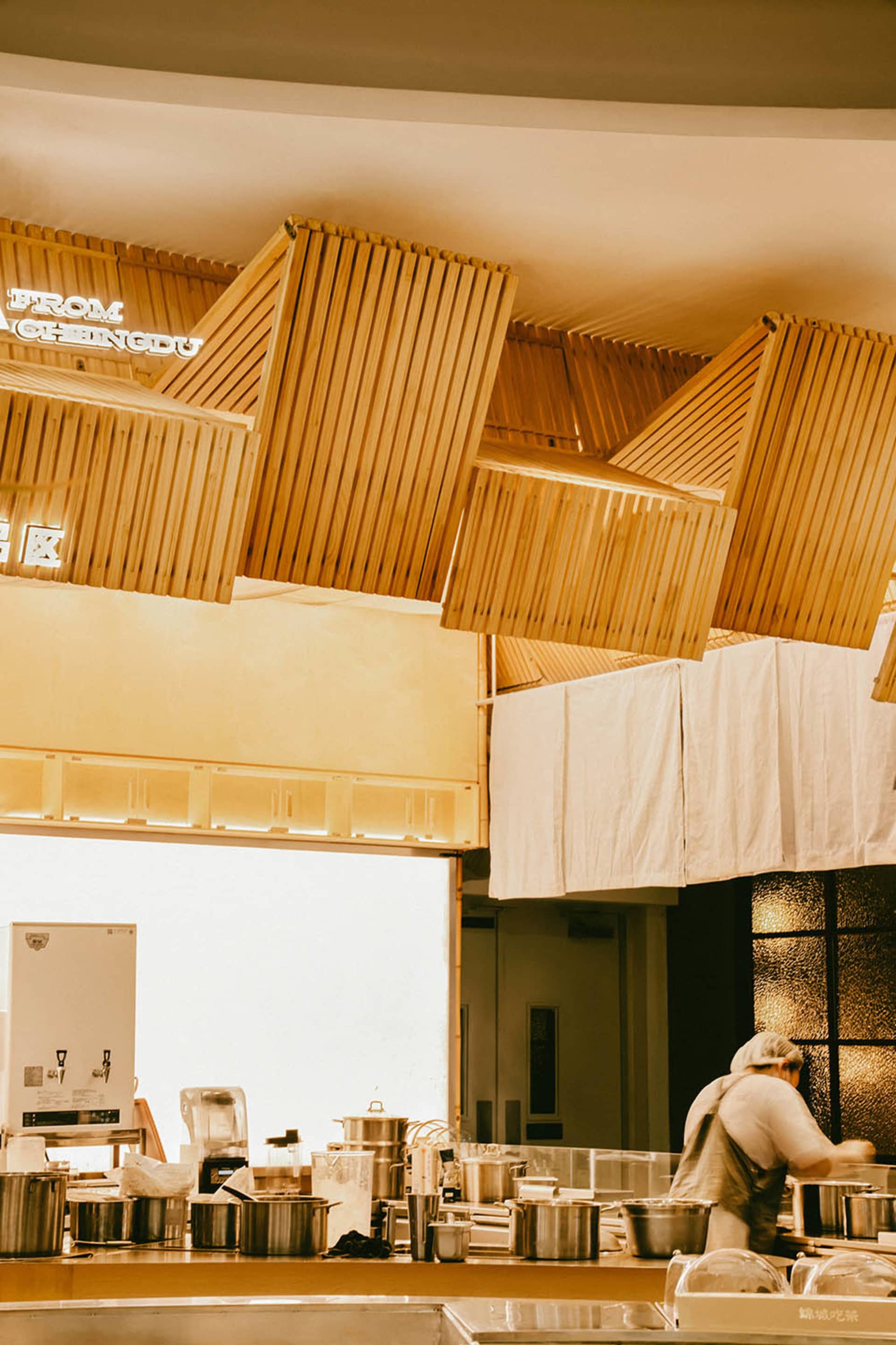 Warm and inviting kitchen dining space with wooden ceiling beams and walls, a refrigerator, dining table, and comfortable seating arrangement