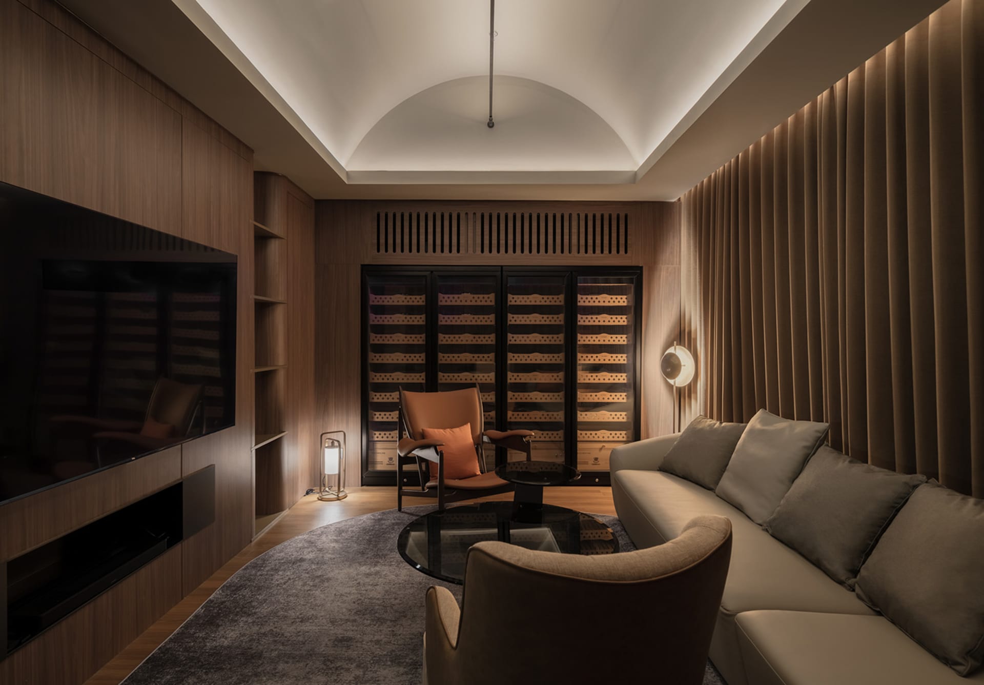 A well-lit living room with a modern design, featuring a couch, chairs, and wine glasses on surfaces