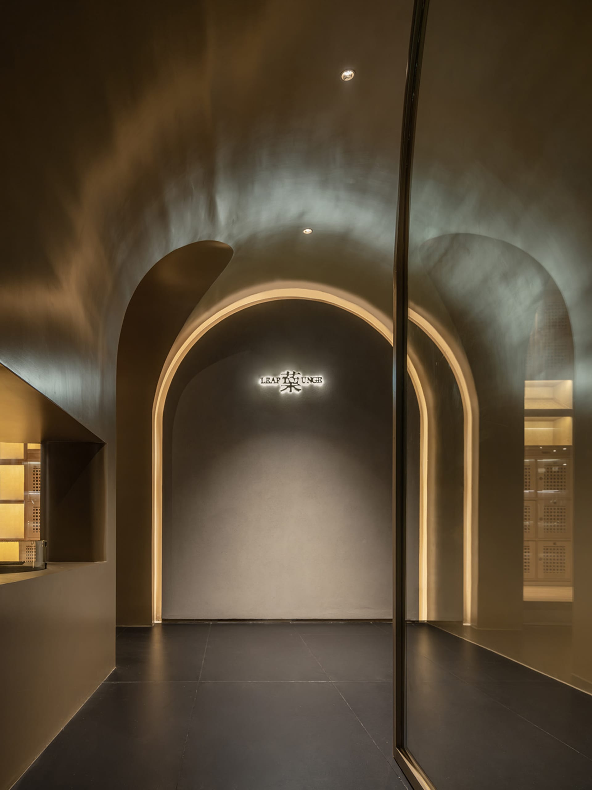 Dimly lit living space with a gold archway, a single chair, and a cozy atmosphere