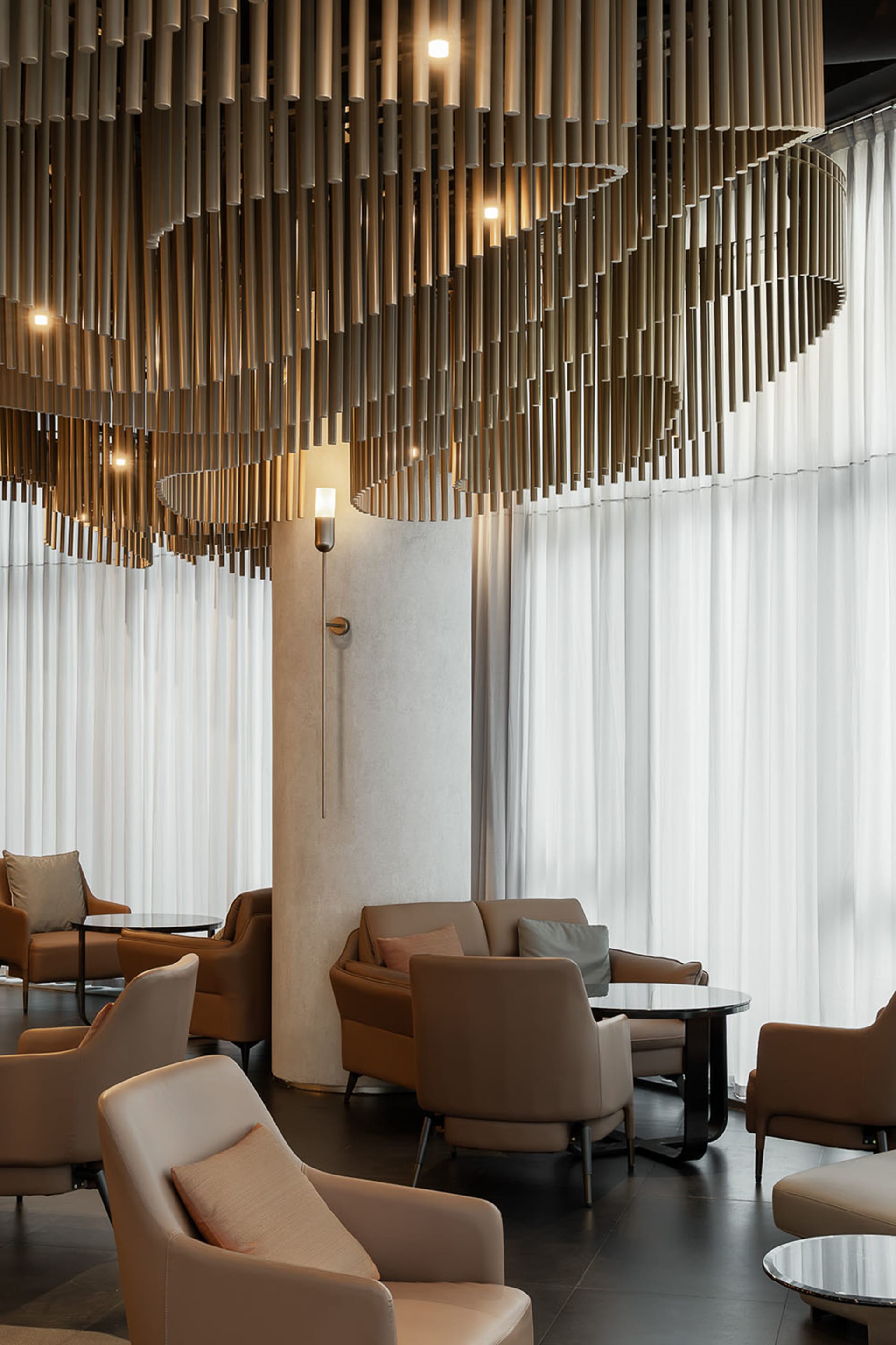 A modern living space with three couches, two chairs, and three dining tables, featuring leather and wood furniture, white walls, and soft warm lighting