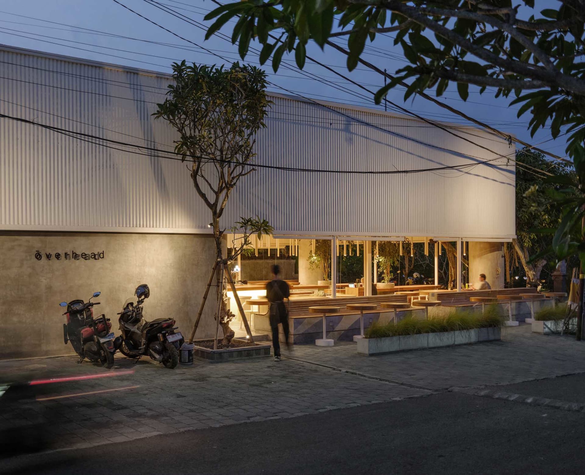 夜晚戶外餐廳場景，設有餐桌、椅子與盆栽，營造溫暖親切的氛圍
