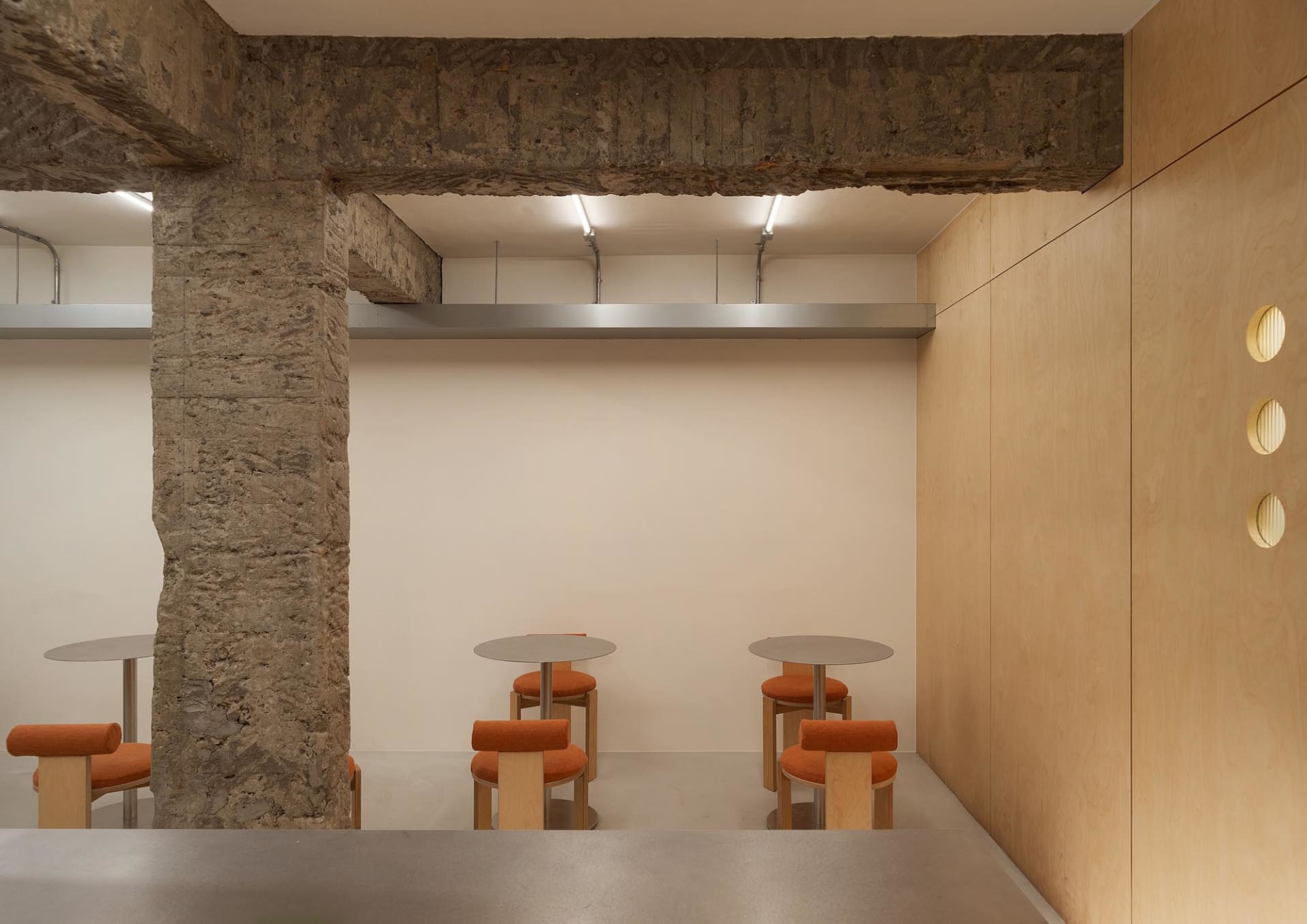 An empty restaurant interior with wooden tables and orange cushioned chairs, creating a warm and inviting atmosphere