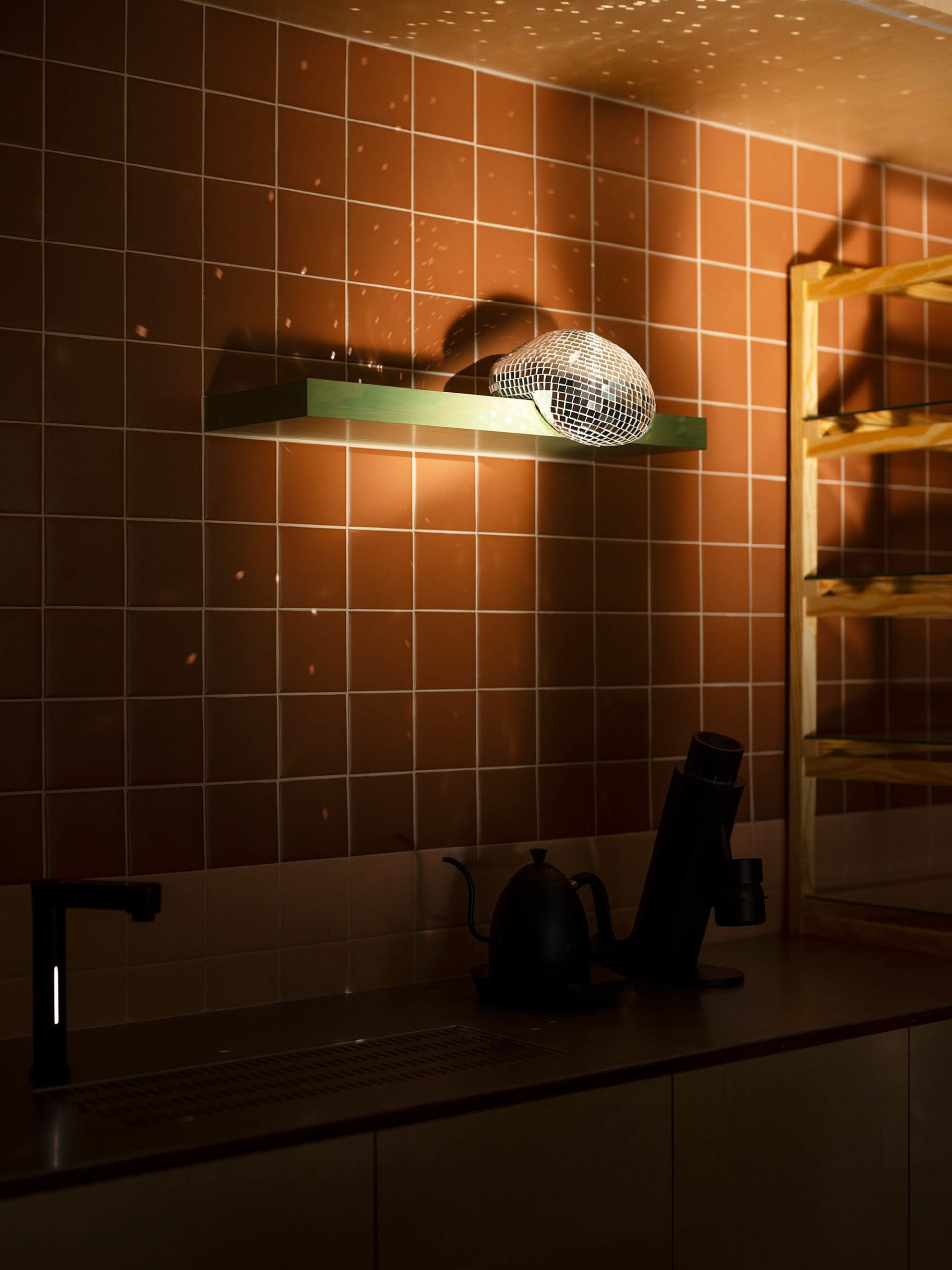 Cozy kitchen with a sink, mirror, and various items on the countertop, including cups, a kettle, and a bottle, with a focus on practicality and organization