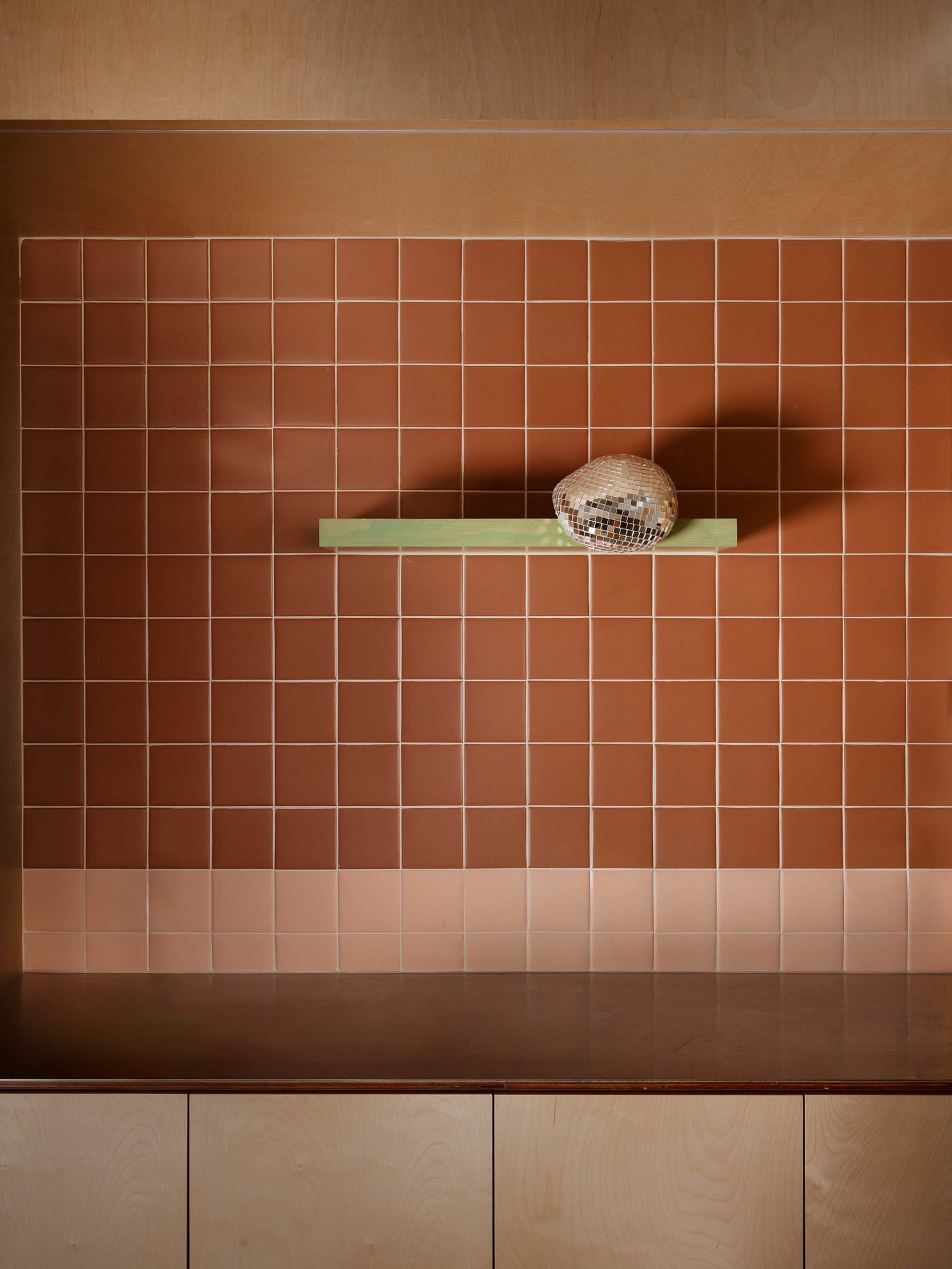 Cozy kitchen space with a tile wall, a wooden-handled hat, and a glass bowl on a shelf, with a functional and inviting atmosphere
