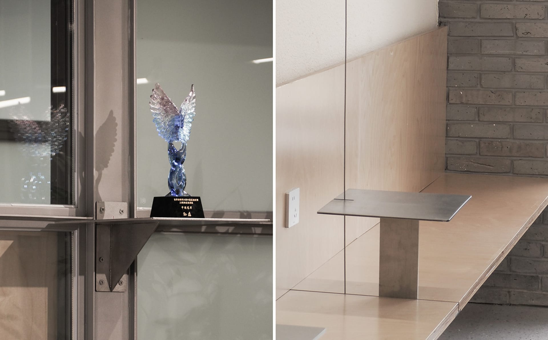 A modern office space with a glass wall and staircase, featuring a reflective surface and a trophy on display, with a clean and organized atmosphere