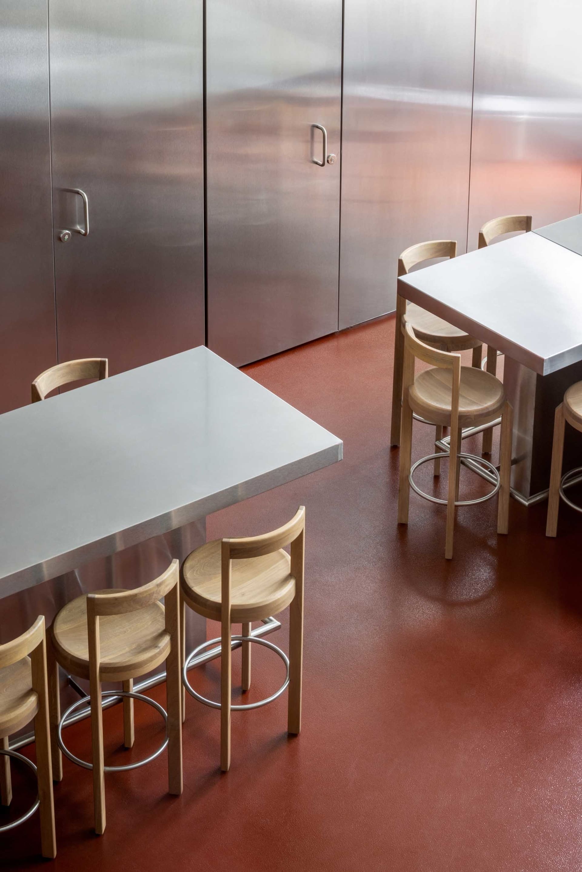 Industrial dining space with a metal table and wooden chairs, well-lit with natural light or overhead lighting