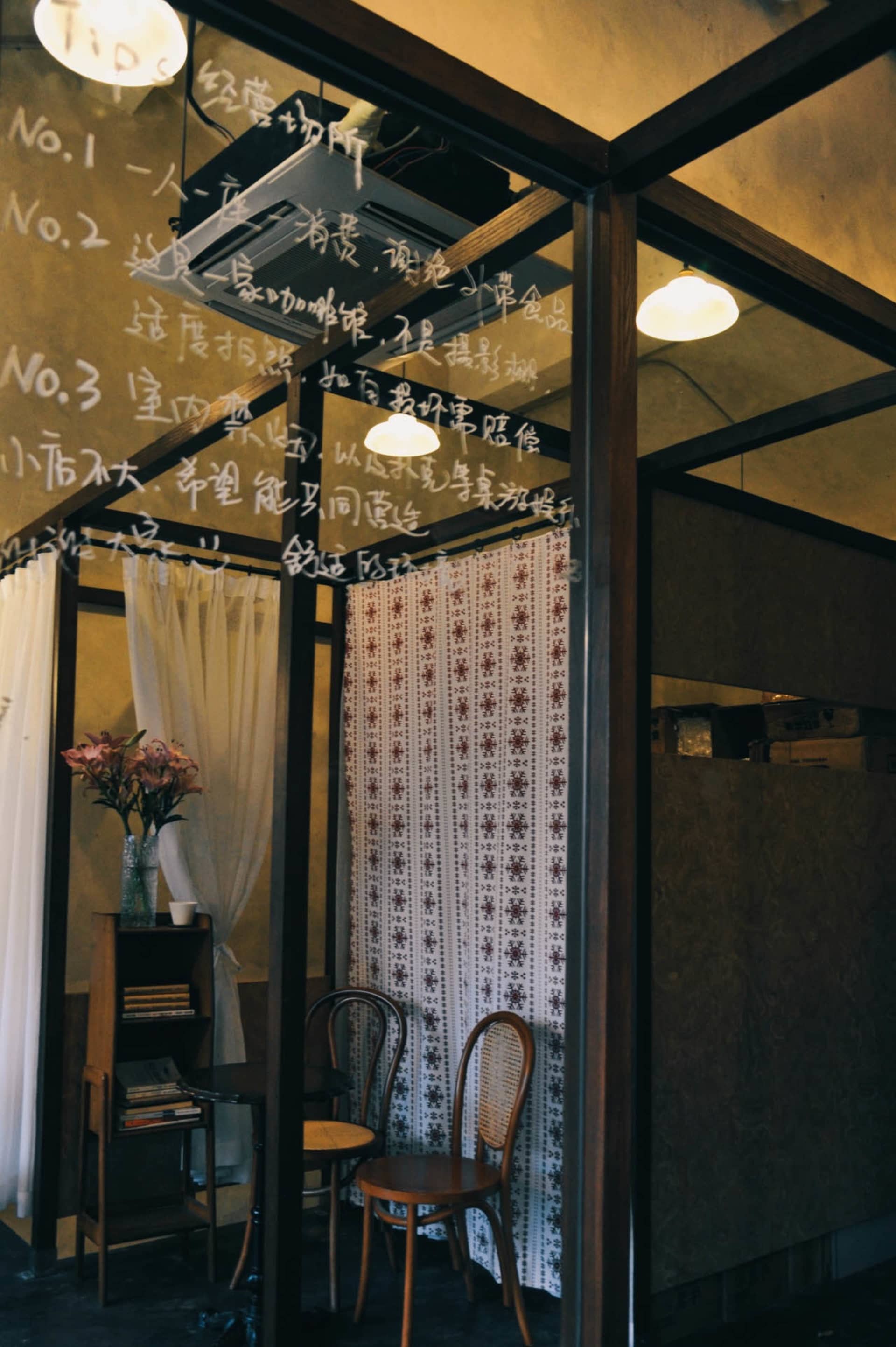 Cozy Asian-style living space with a wooden door, two chairs, a table, and a vase, dimly lit for a warm atmosphere