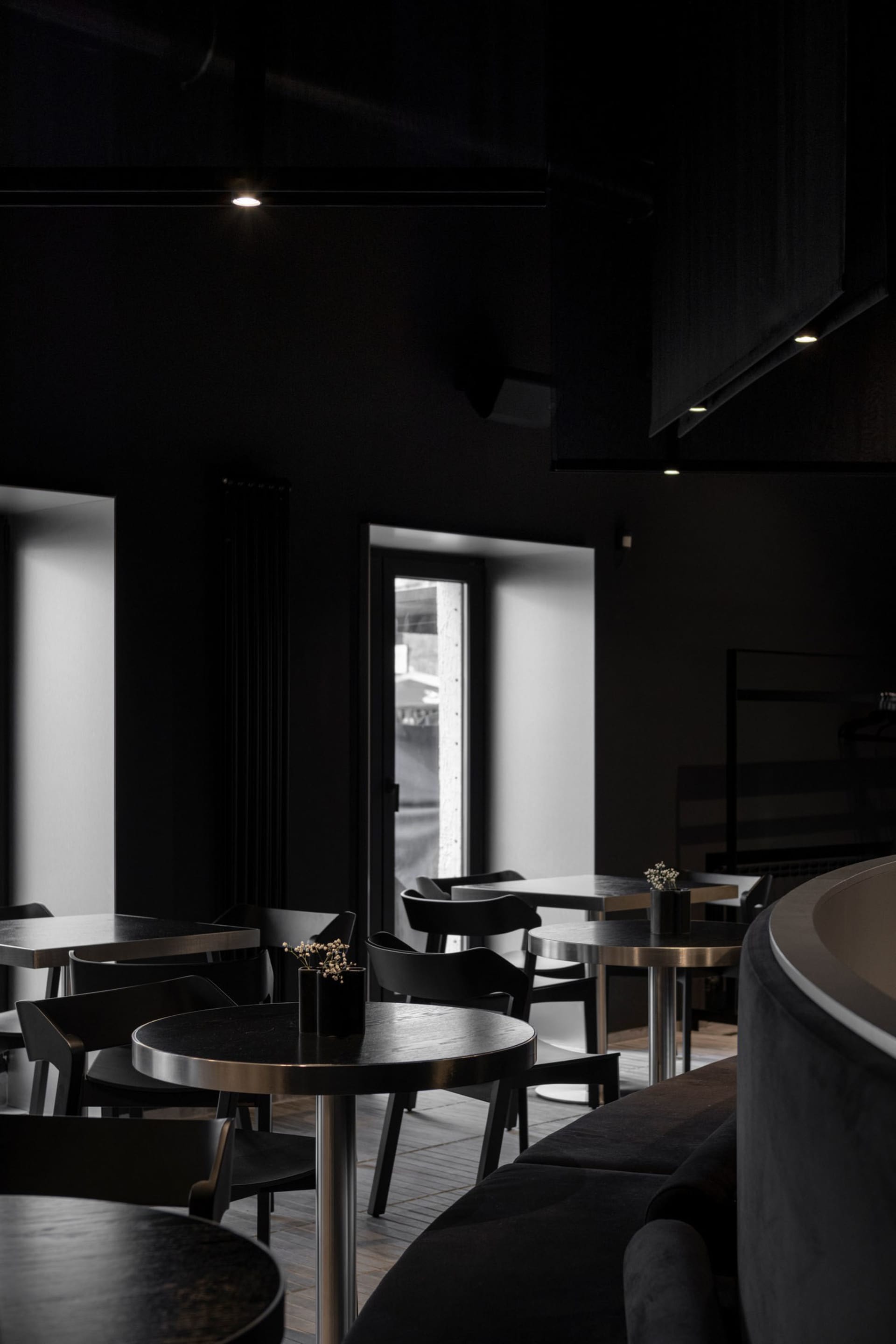 Modern restaurant interior with black walls, dining tables, and chairs, creating a stylish and inviting atmosphere