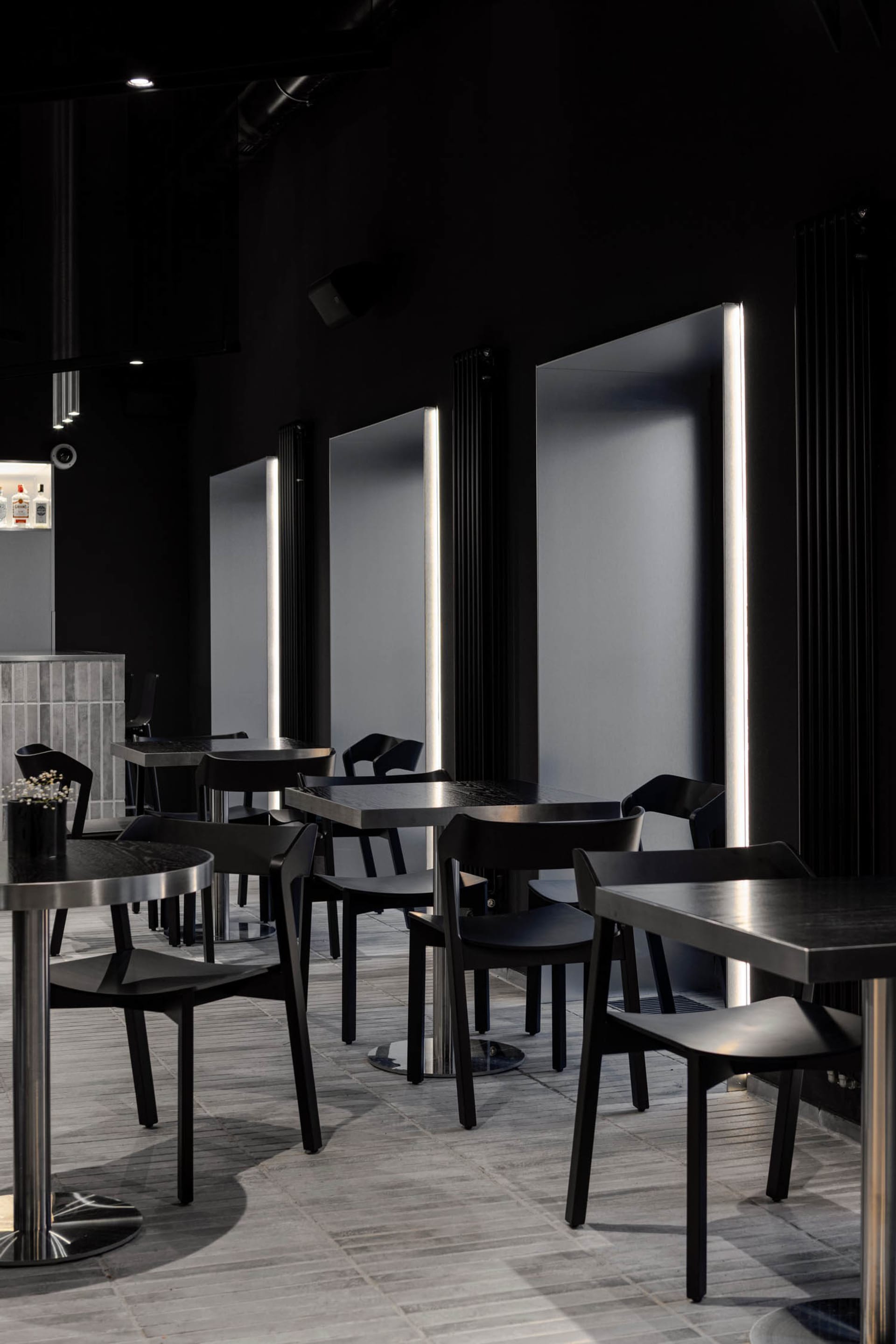 Sophisticated restaurant interior with black tables and chairs, multiple dining tables, and a modern atmosphere