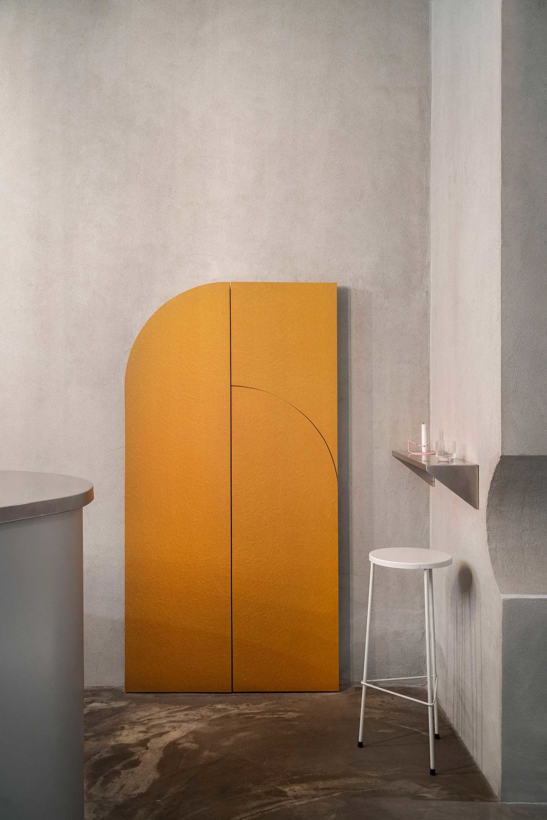 Modern bathroom with a yellow wall divider, two small tables, a countertop, and a sink, featuring a well-lit and inviting atmosphere