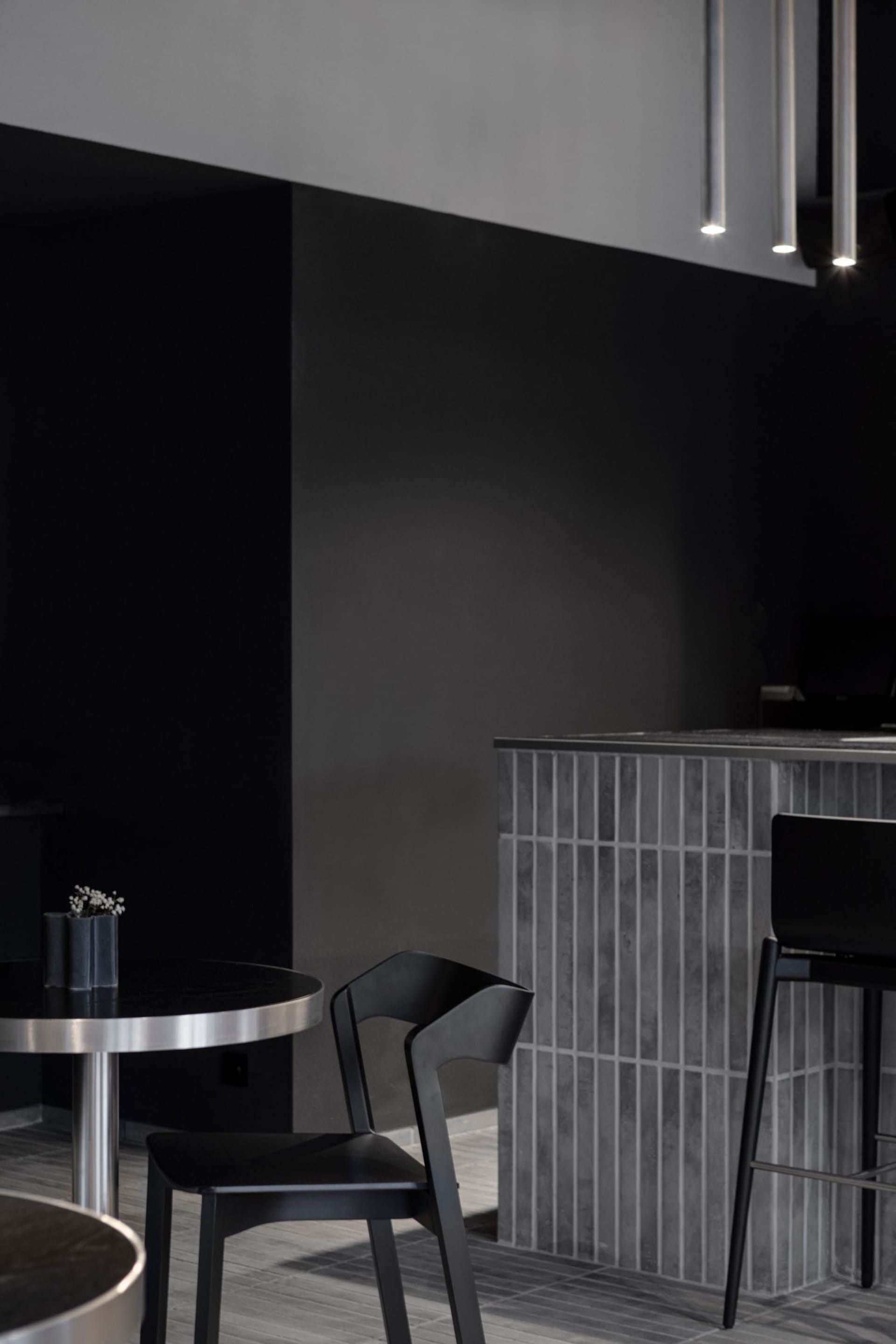 Modern cafe interior with a black countertop, dining table, and two chairs, featuring a warm ambiance and sleek design