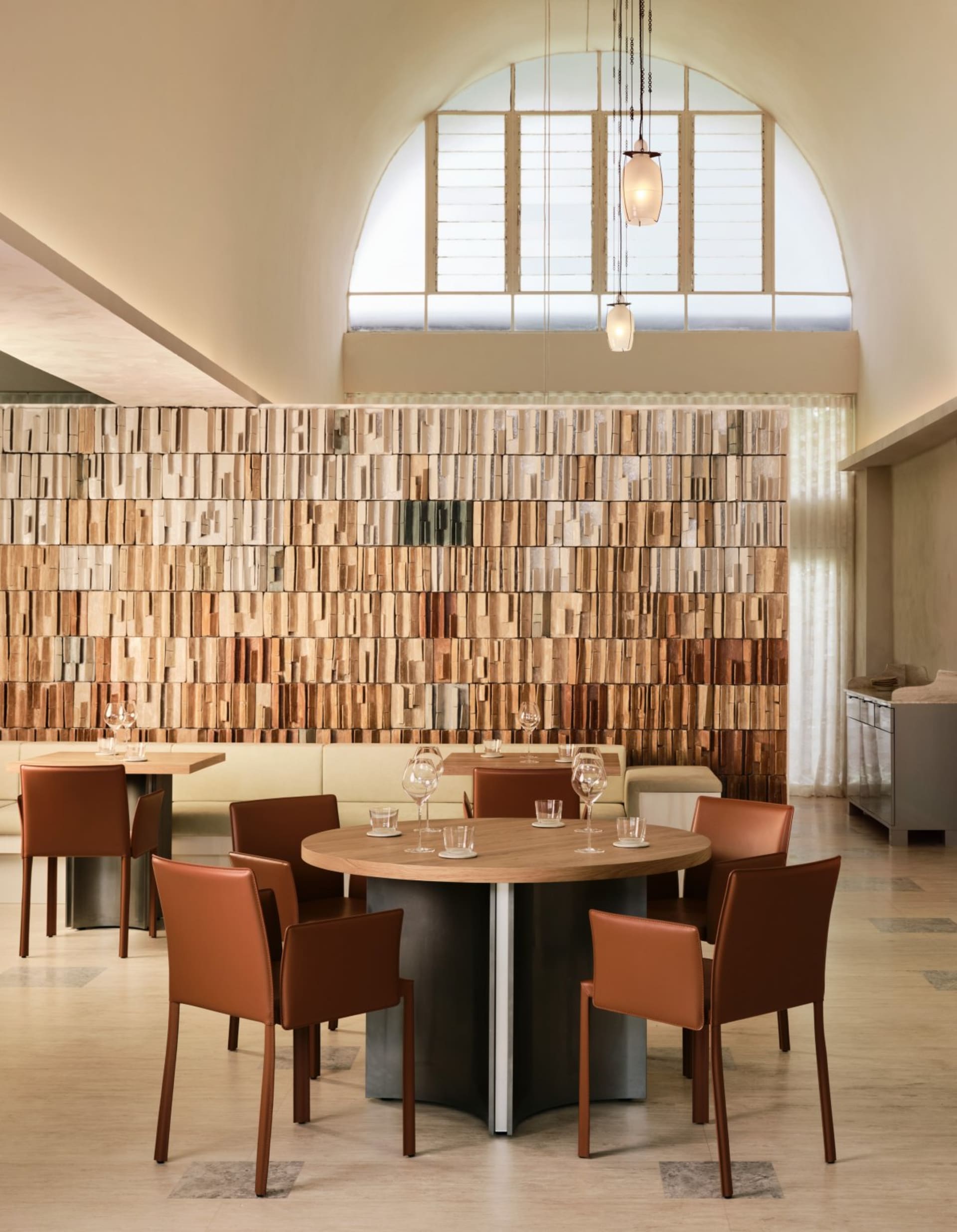 Cozy restaurant interior with wooden walls, tables, and chairs, featuring wine glasses and a warm atmosphere