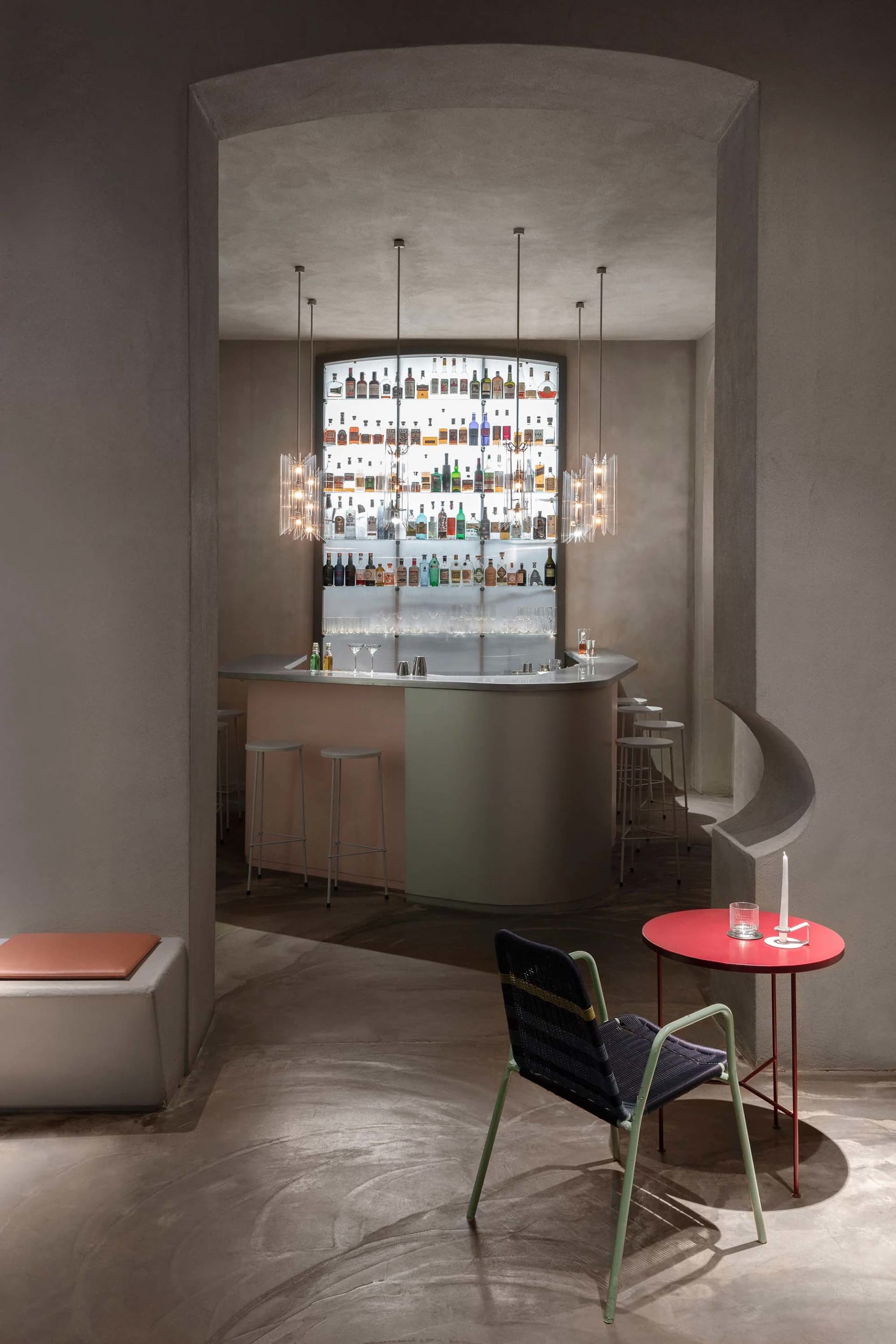 A stylish bar area with a silver counter, wine rack, chairs, and dining tables, creating a welcoming space for socializing and dining