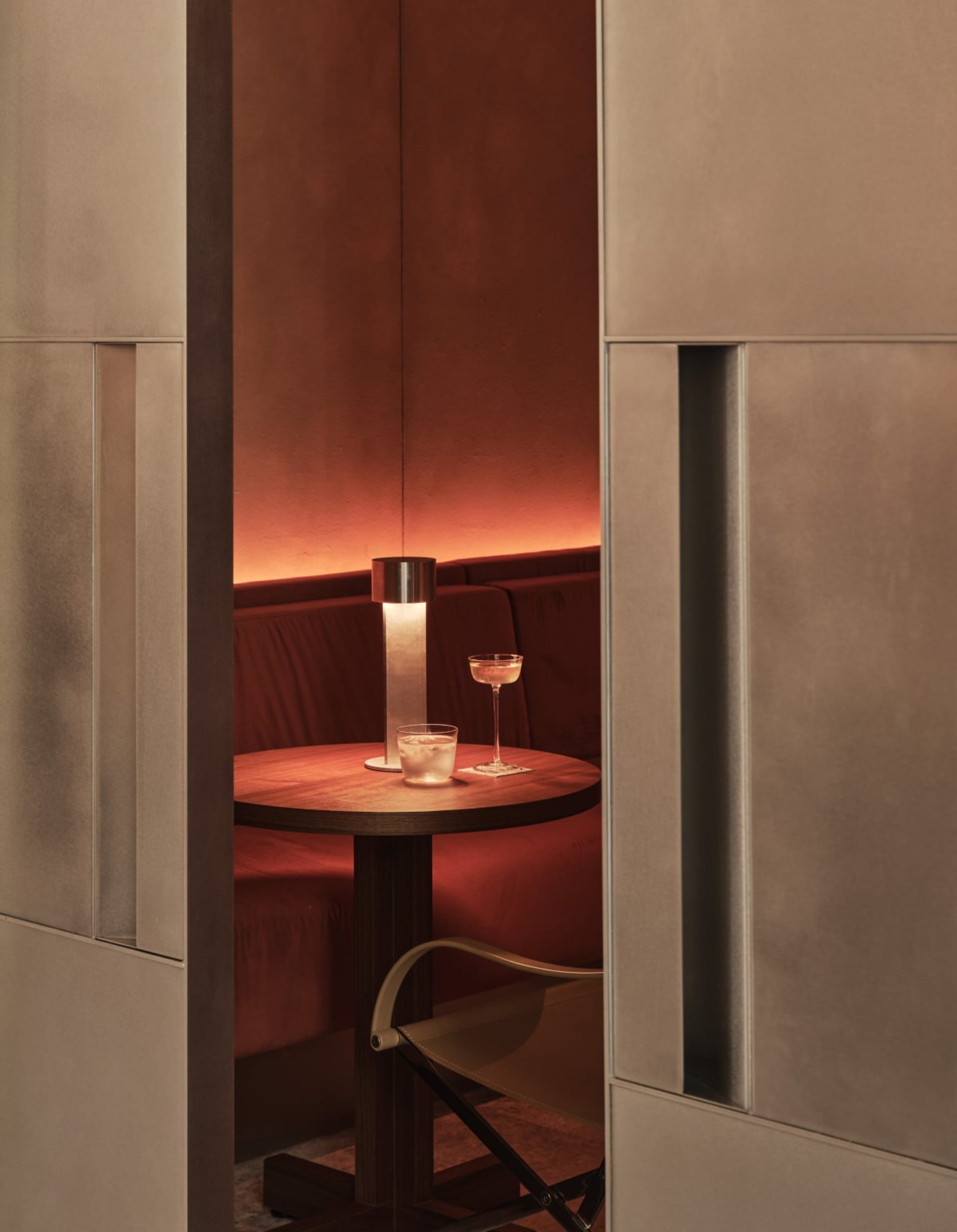 A dimly lit room with a wooden table, wine glasses, and a bottle of wine, surrounded by chairs in a relaxing and intimate atmosphere