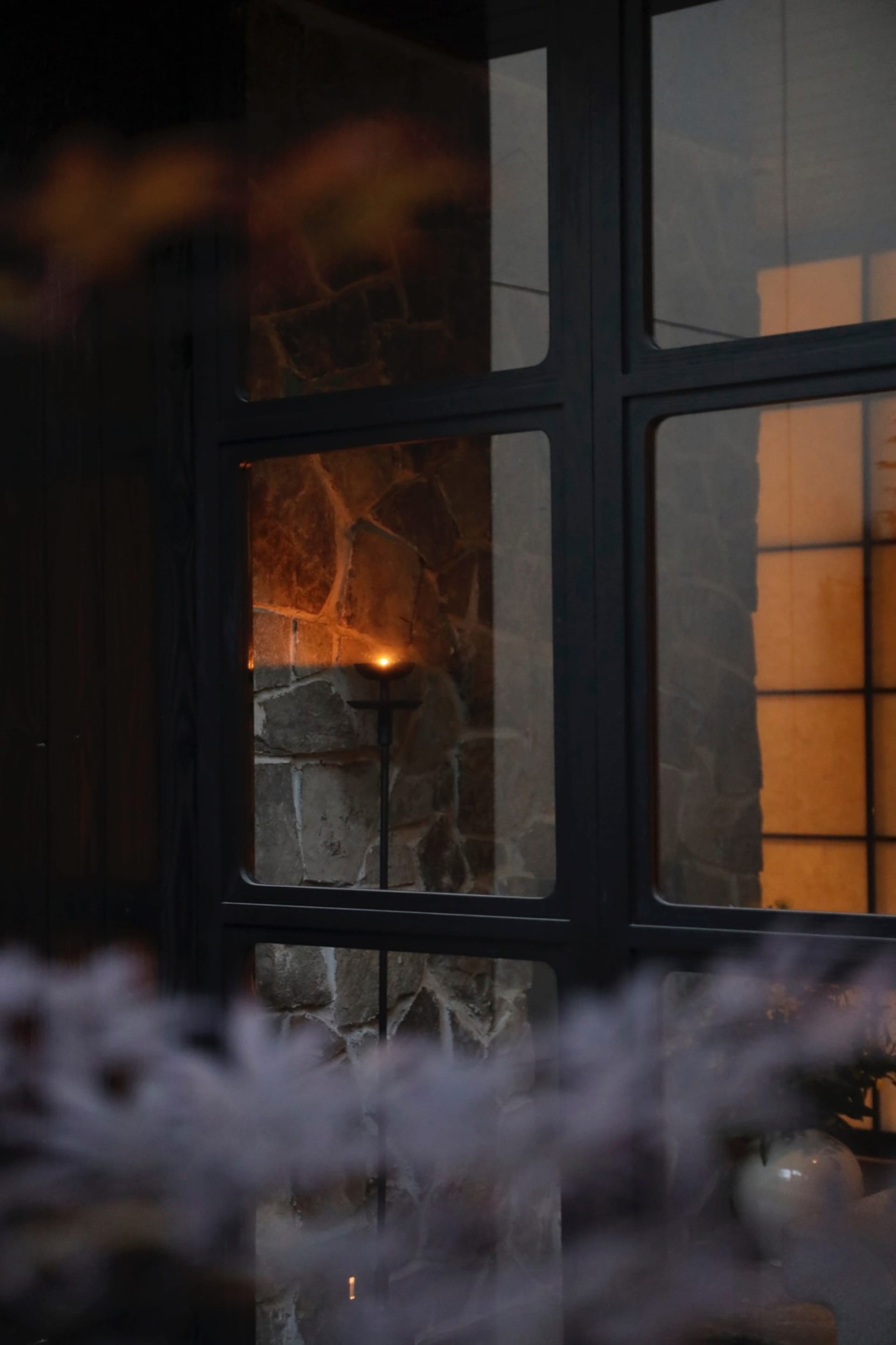 A serene home interior with a glass window and a lit candle creating a warm atmosphere