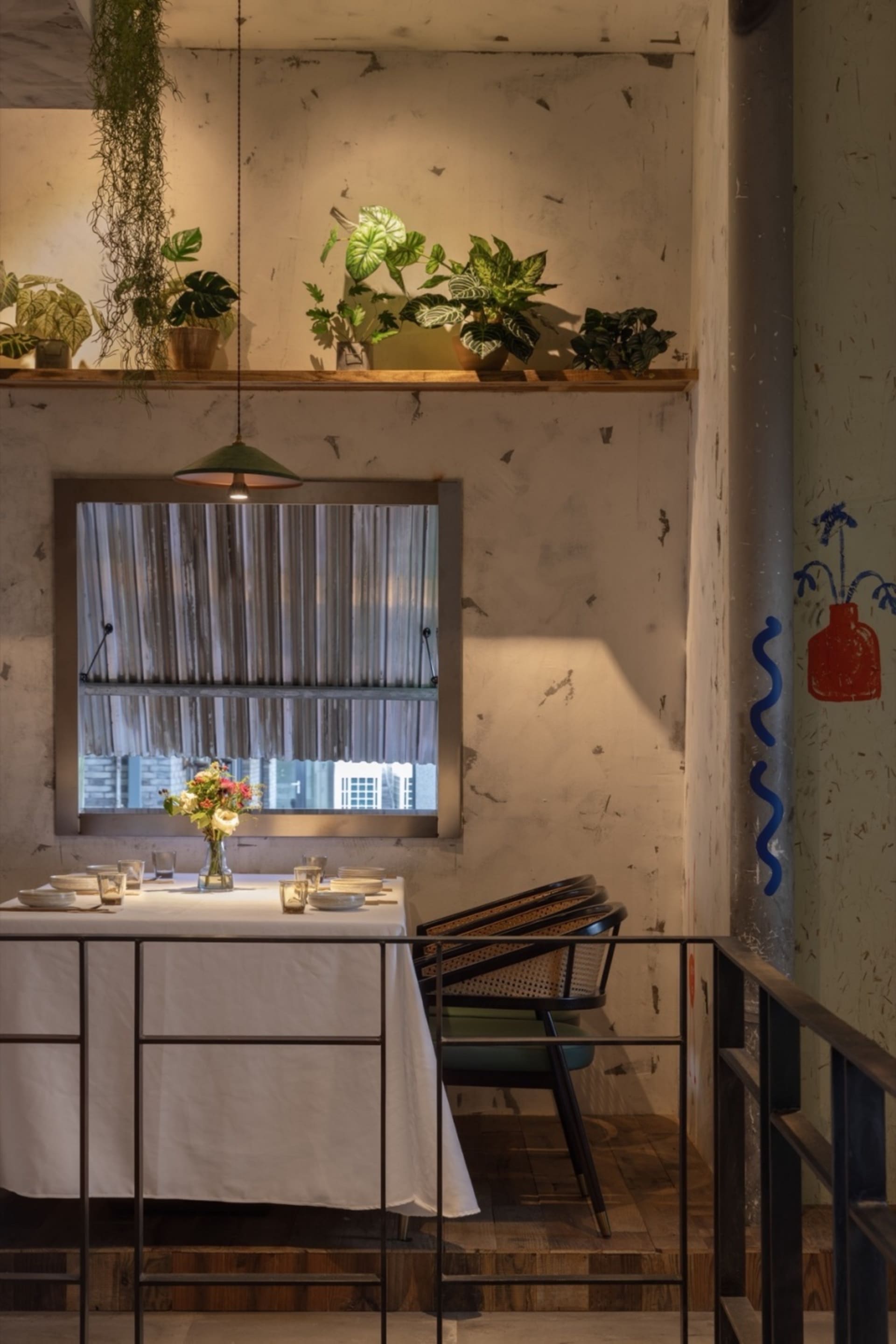A well-decorated dining area with a white table, chairs, potted plants, and flowers, creating a cozy atmosphere