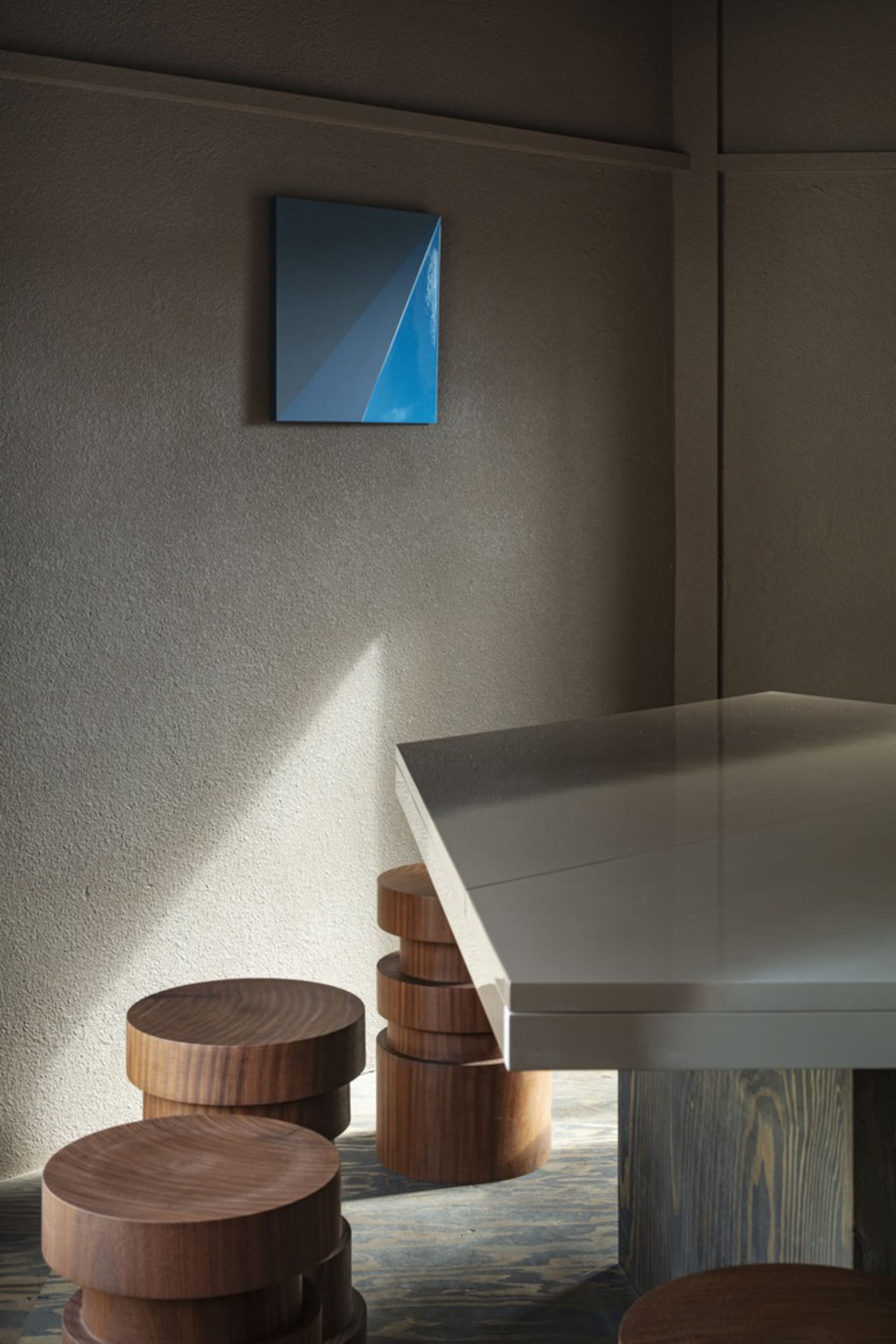 A dining table surrounded by four wooden stools, with two chairs on each side, creating a cozy seating arrangement in a modern yet warm space