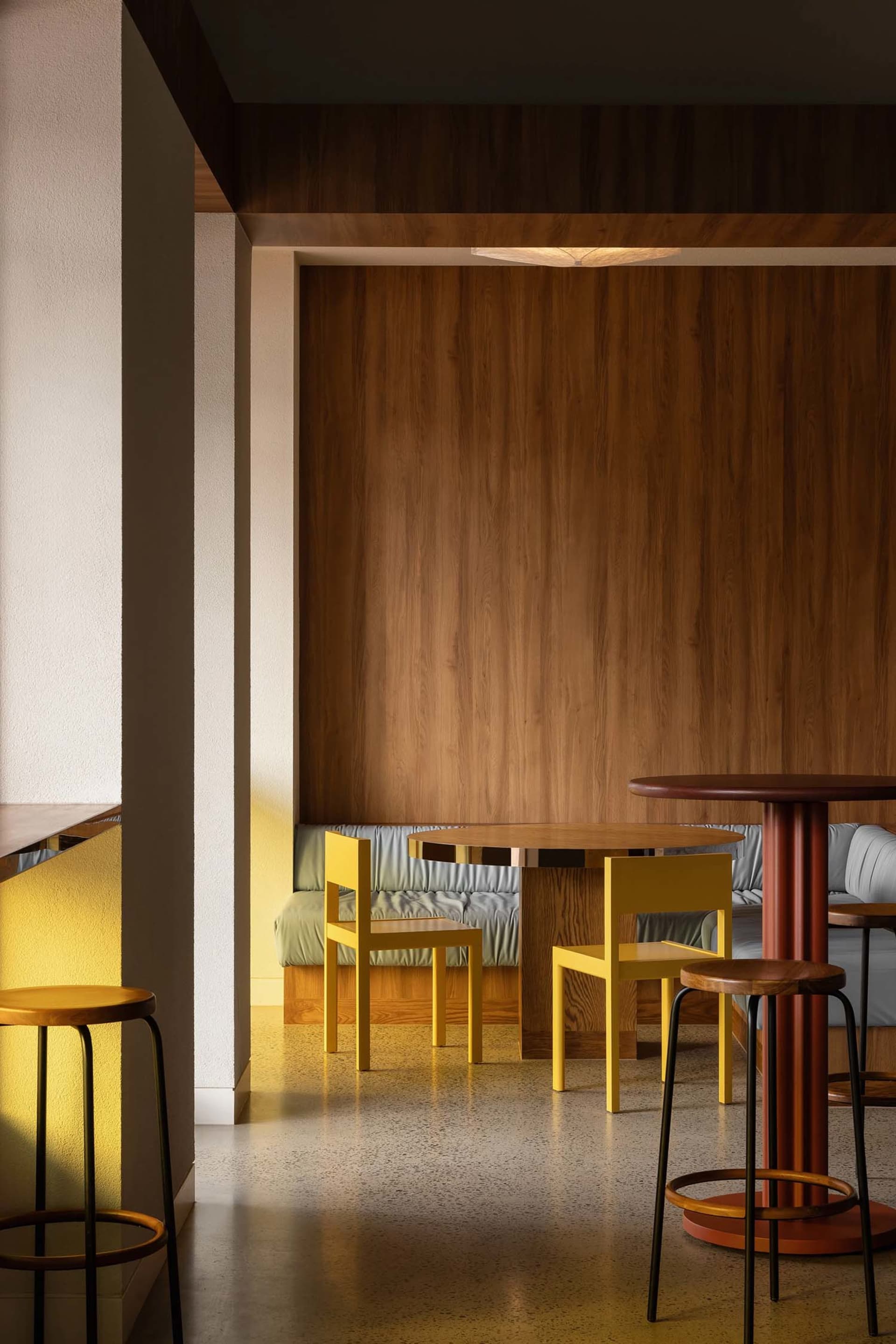 Cozy dining area with wooden walls and floors, featuring a table and chairs, a couch in the background, and a modern inviting atmosphere