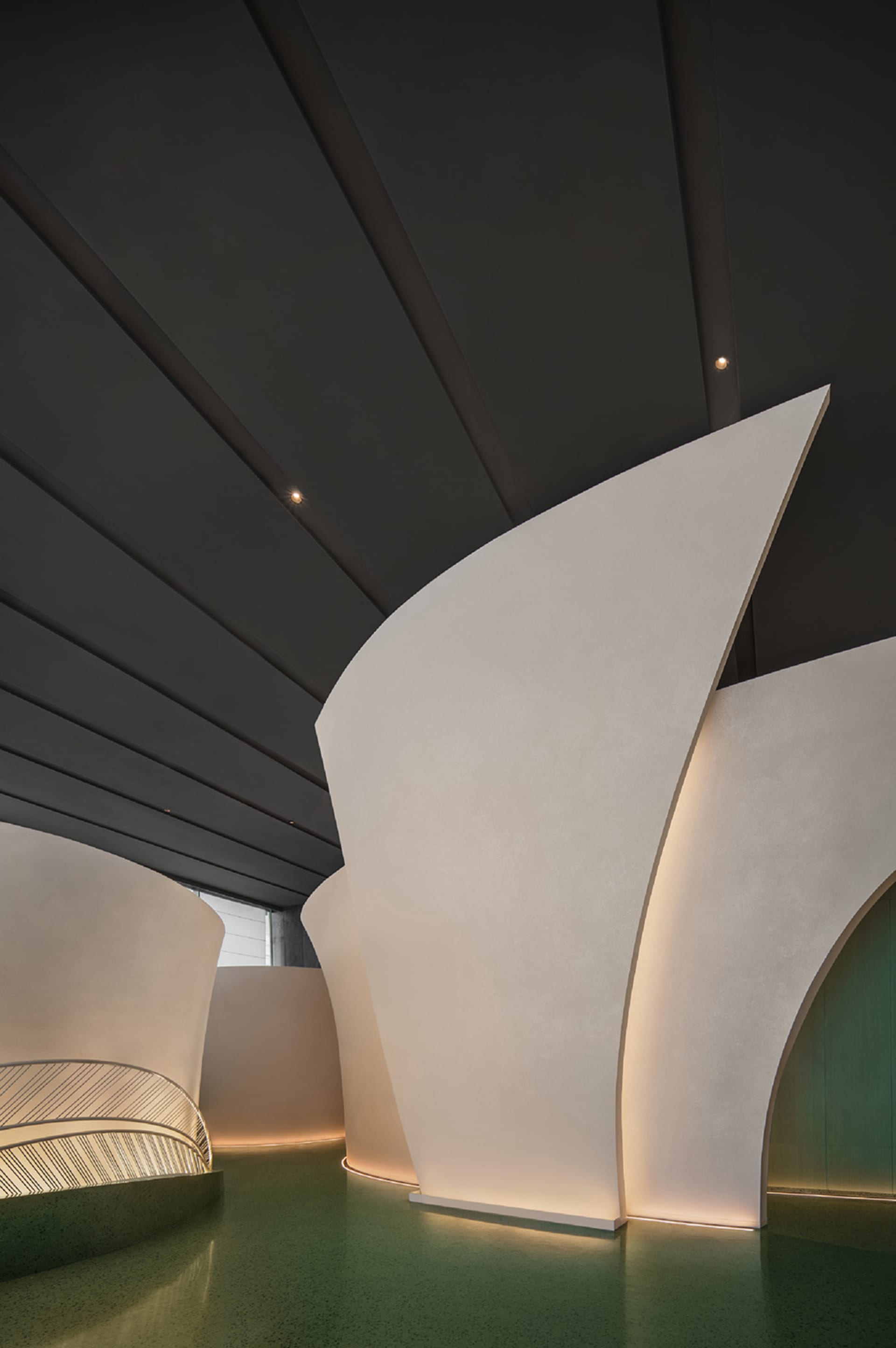 A modern interior space with a curved white wall, two doorways, and a minimalist aesthetic