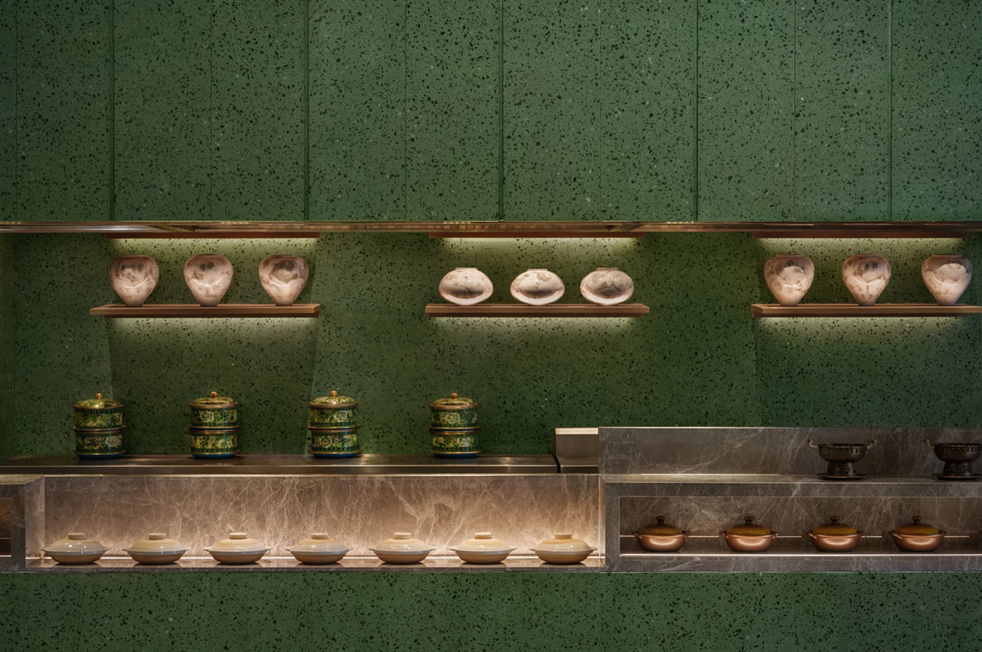 A clean and organized kitchen with green walls and a countertop featuring variously sized bowls and two cups, emphasizing functionality and practicality
