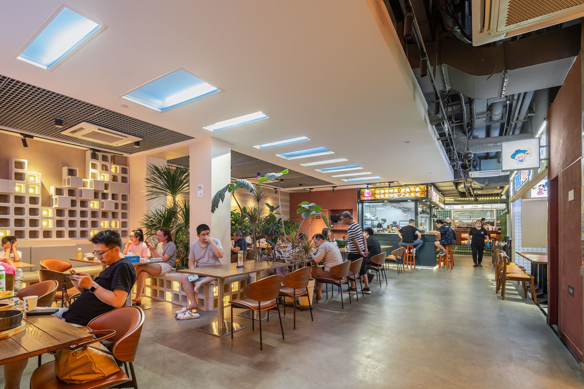 A casual dining area in a restaurant with wood and metal elements, featuring tables and chairs, patrons enjoying meals and conversation