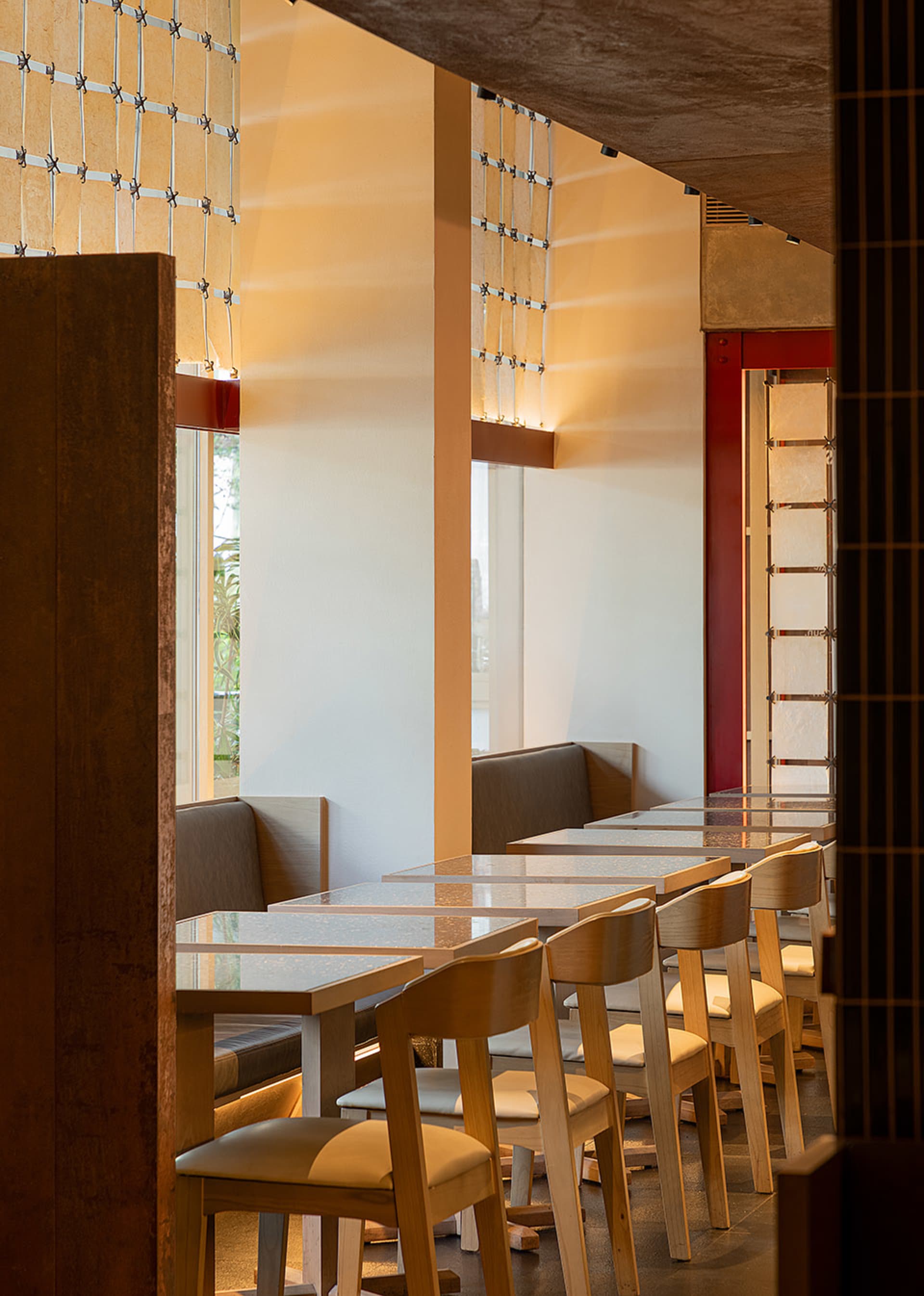 Modern restaurant dining area with glass tables, white walls, and dim lighting creating a cozy atmosphere