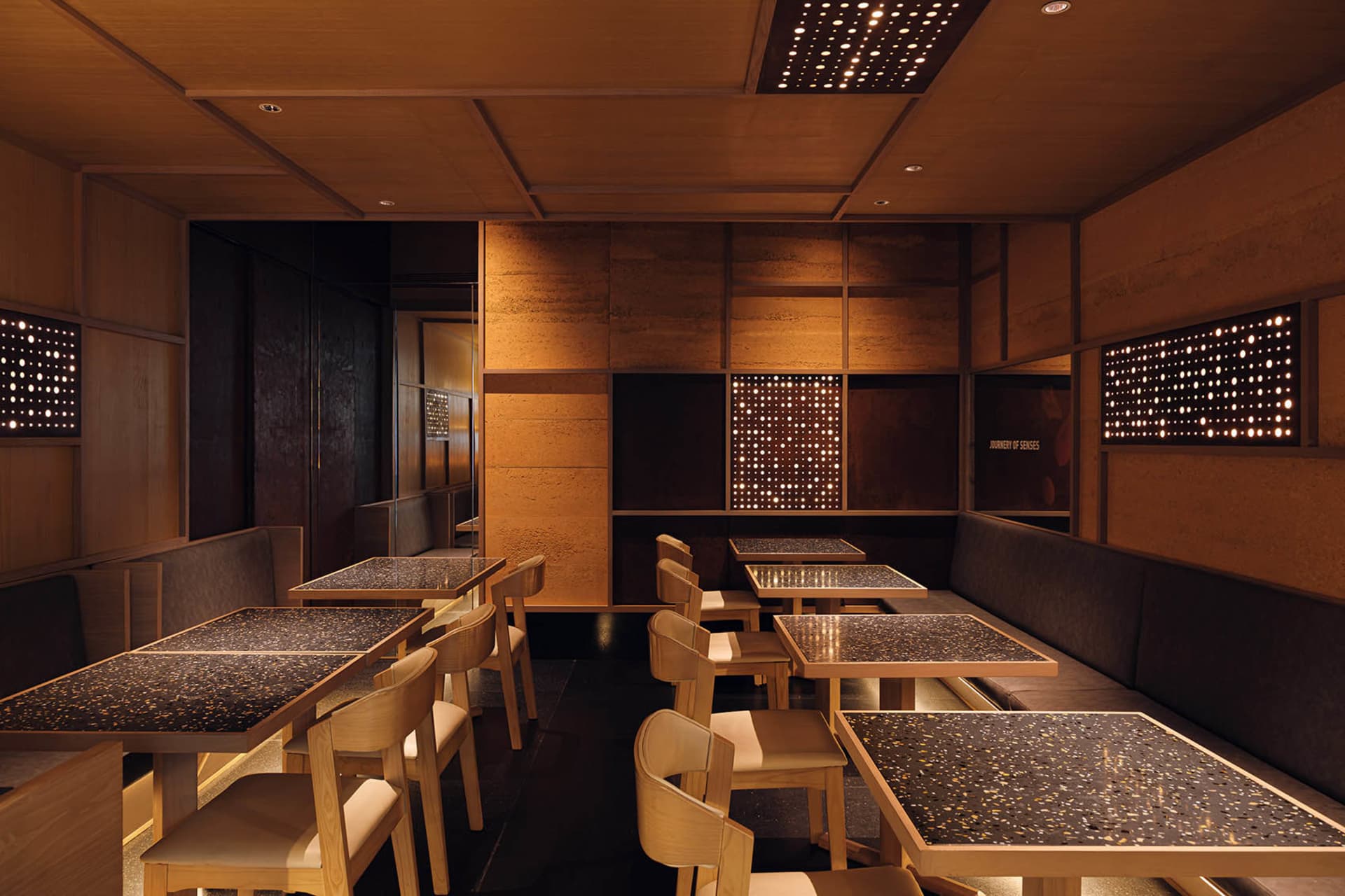 A modern restaurant interior with wooden walls and floors, featuring multiple dining tables and chairs, creating a warm and inviting atmosphere