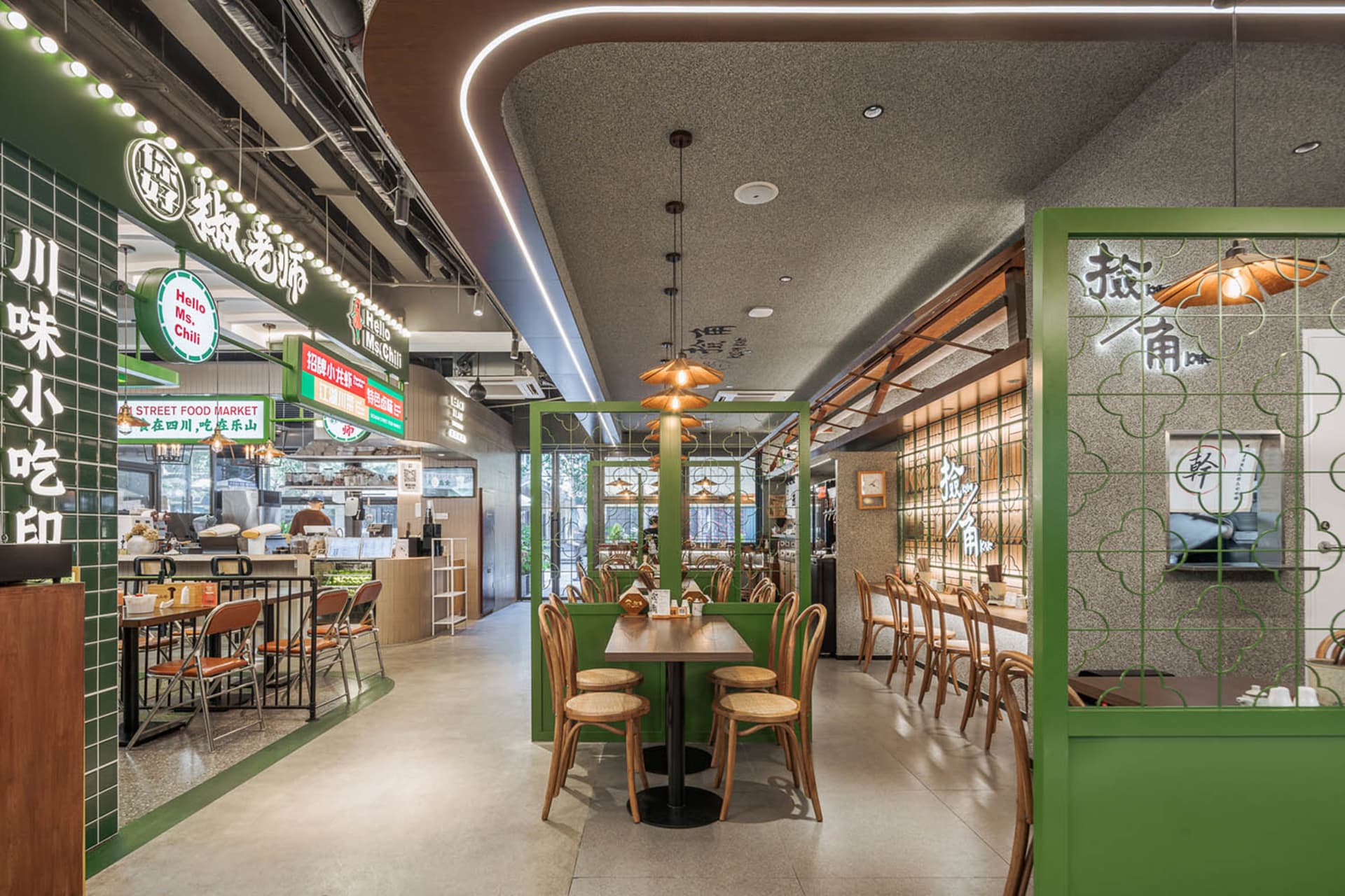 A modern Asian restaurant interior with multiple dining tables, chairs, and green accents on the walls and flooring, creating a vibrant and inviting atmosphere