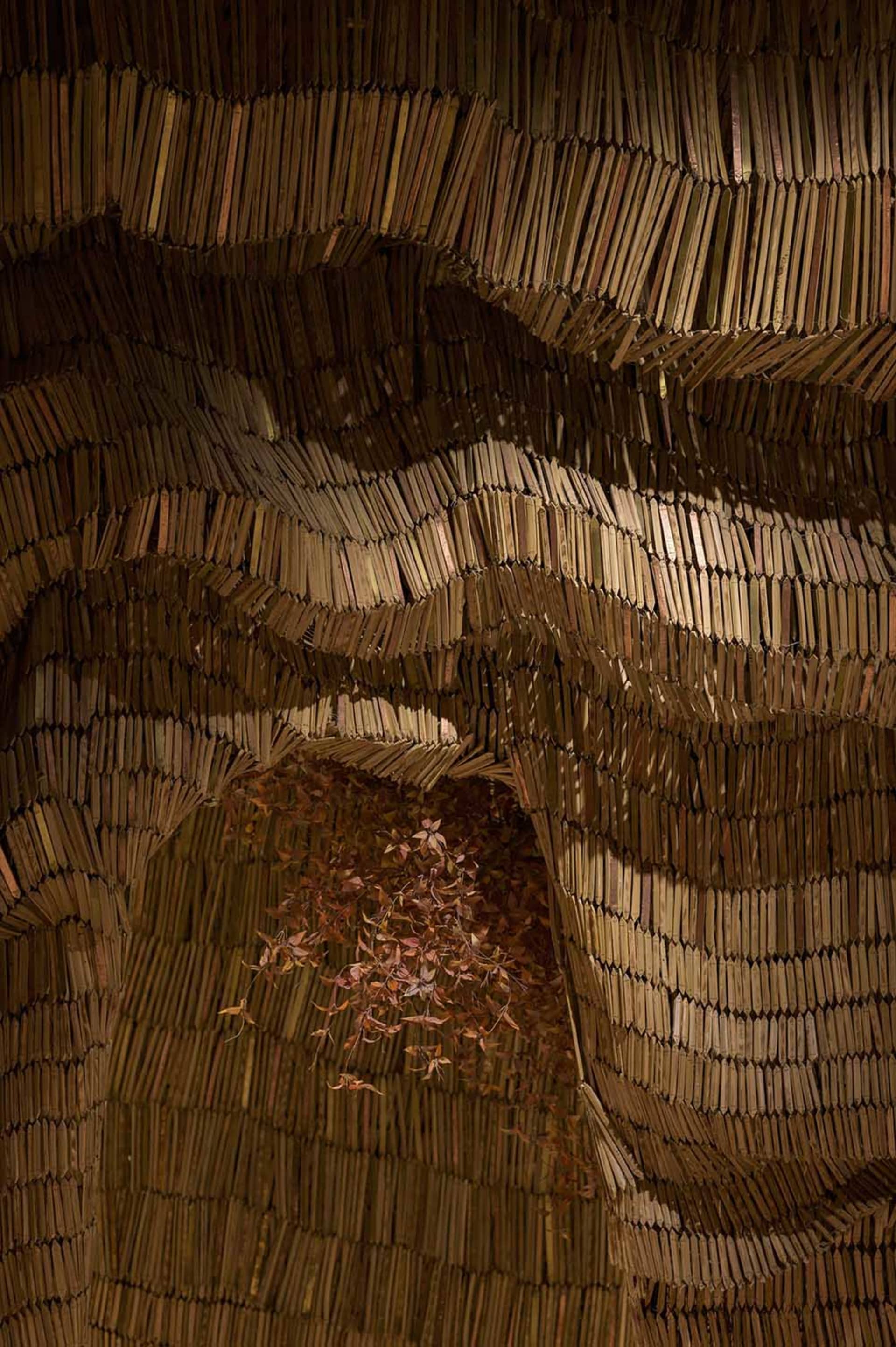 A three-dimensional book structure resembling a cave or tunnel, created from stacked books, with intricate arrangement and artistic design