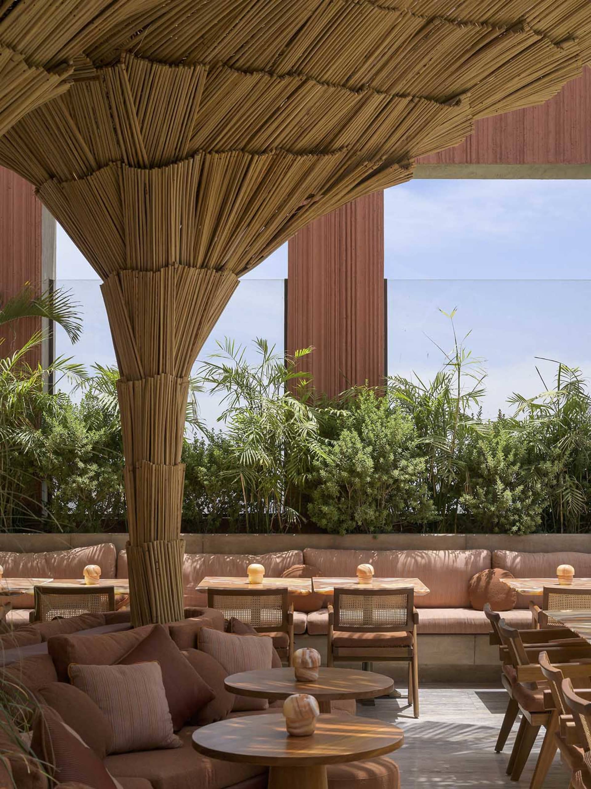 A modern restaurant patio with couches, chairs, and wooden furniture, surrounded by a sophisticated and elegant atmosphere