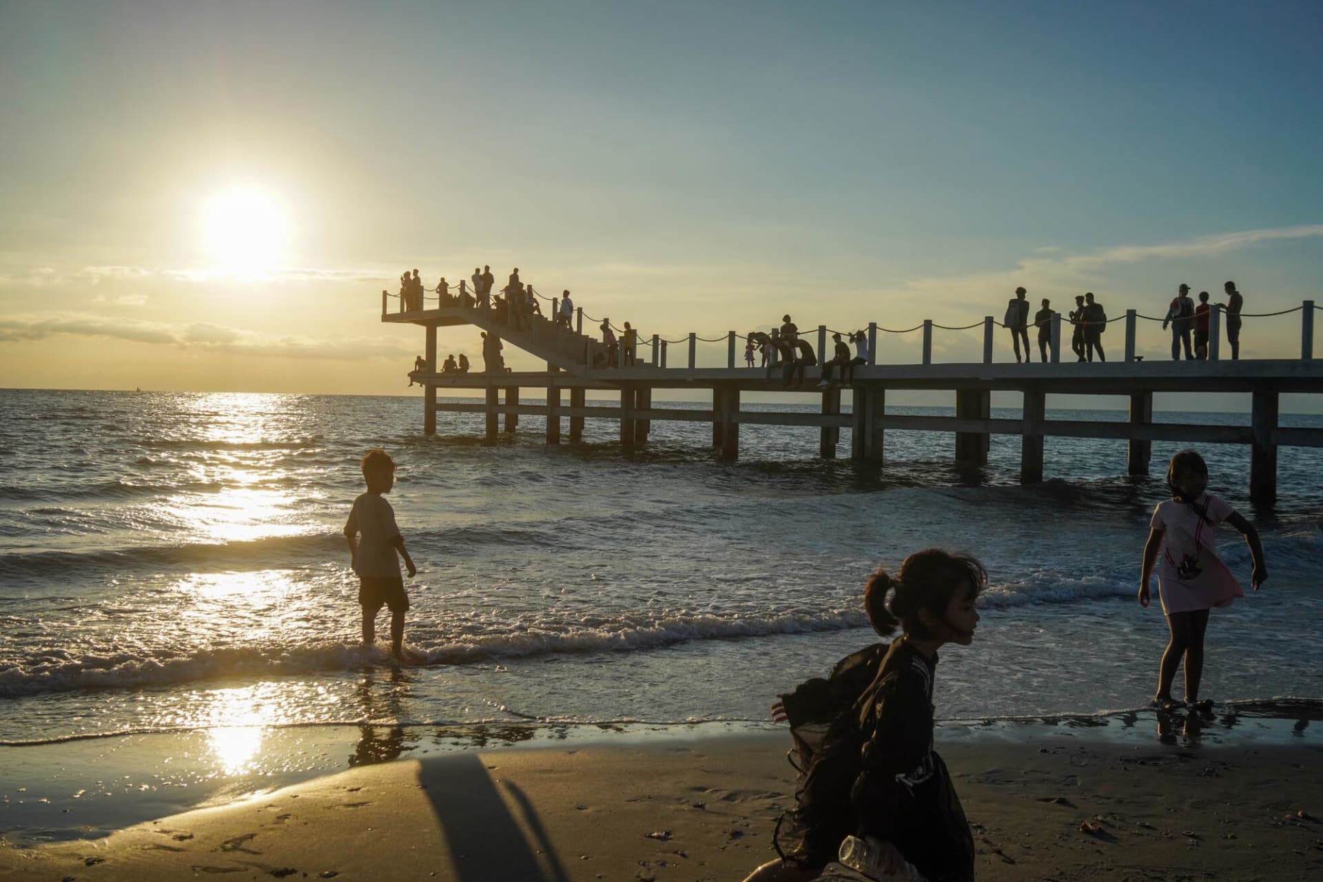 A relaxed beach scene at sunset with people enjoying the ocean view