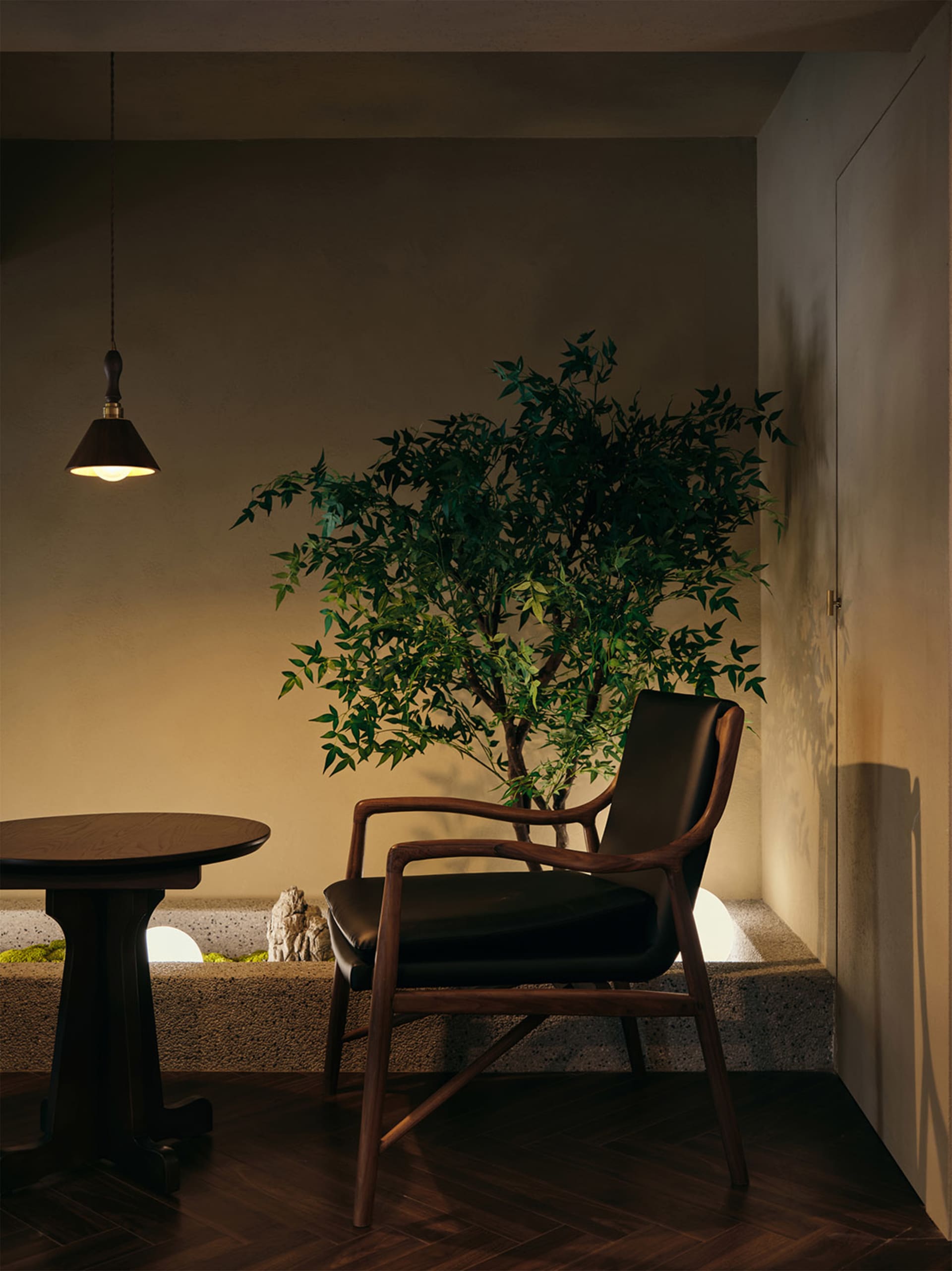 A cozy living area with a black chair and a smaller chair, a potted plant, and a vase on the dining table
