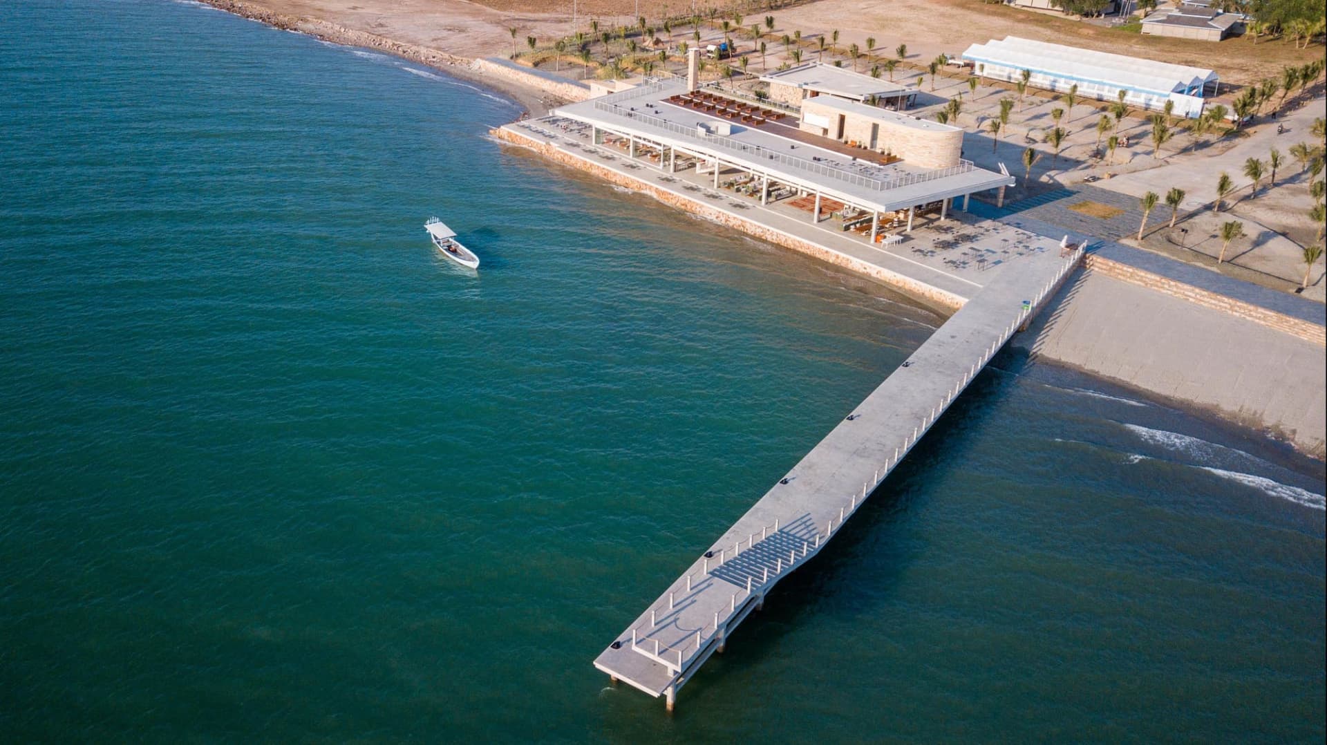 A serene oceanfront pier with benches, boats, and a picturesque view