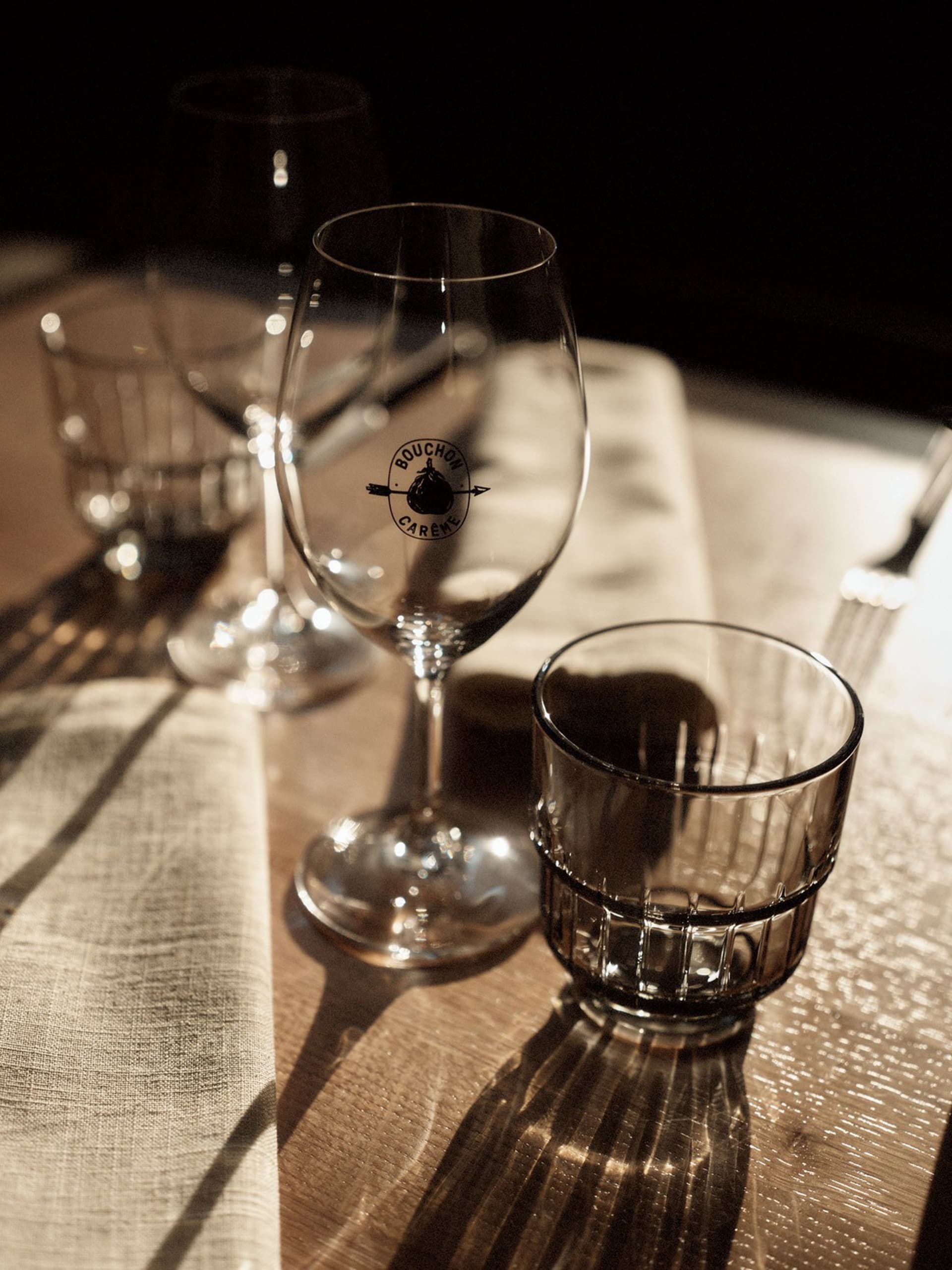 木質餐桌擺放著酒杯、水杯與酒瓶，為晚餐聚會營造溫馨氛圍