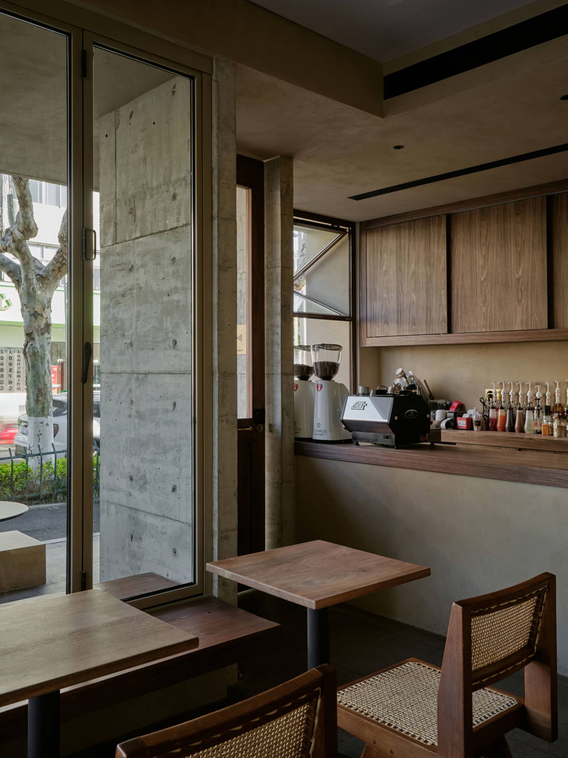Cozy cafe interior with wooden accents, tables, chairs, and a kitchen area with appliances and bottles