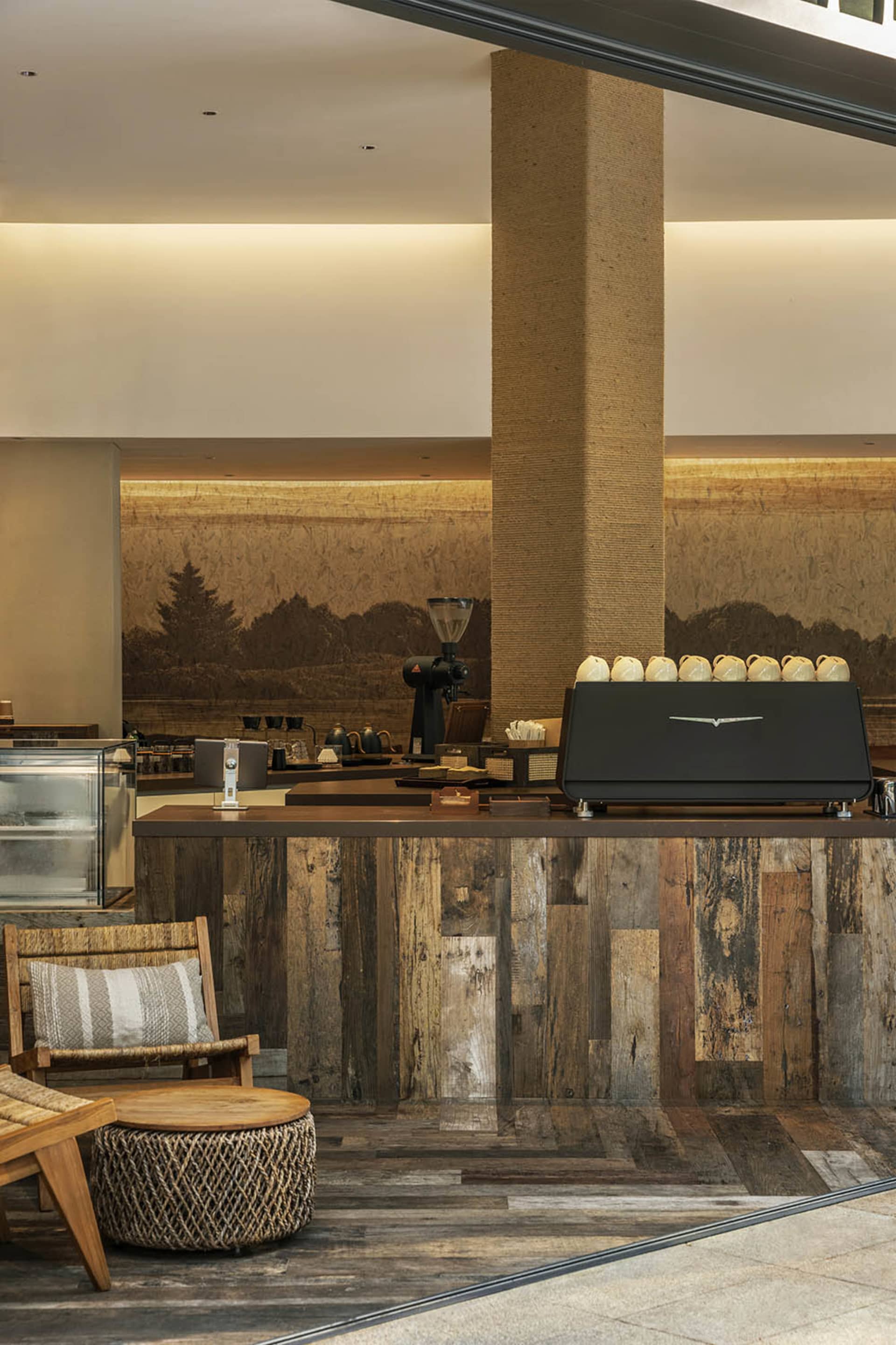 Warm and inviting coffee shop interior with a wooden countertop, black espresso machine, and several cups on the counter