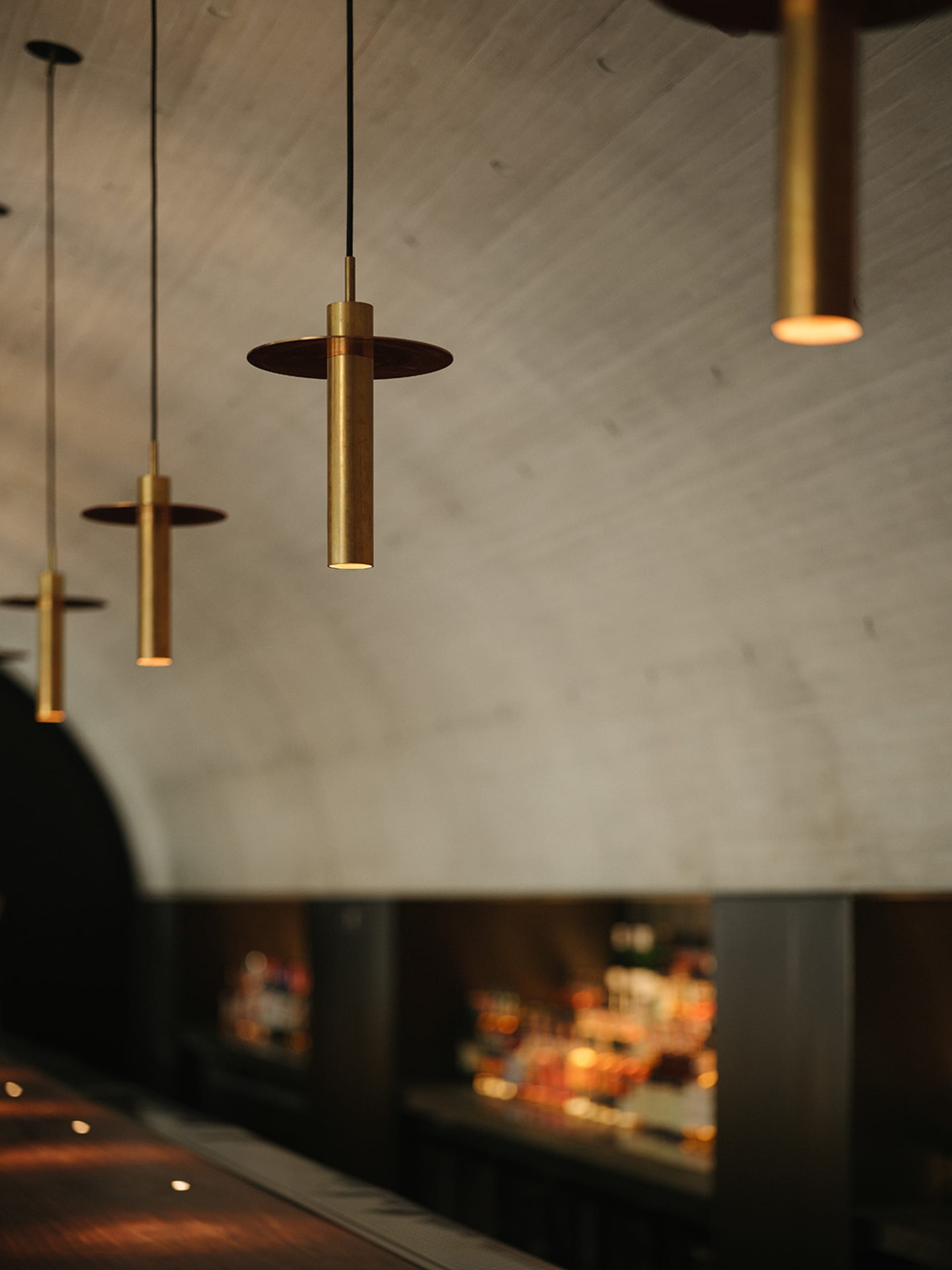 A casual bar area with concrete walls, bottles on various surfaces, and a modern industrial feel