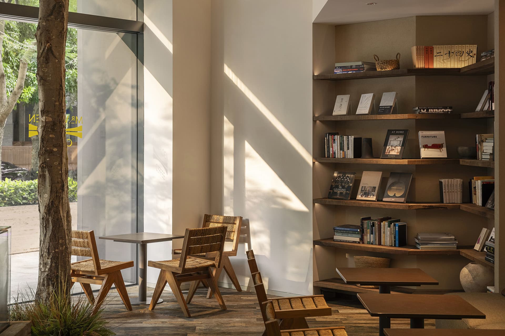Cozy modern living space with a dining table, chairs, bookshelves, and a window, featuring clean lines and neutral tones