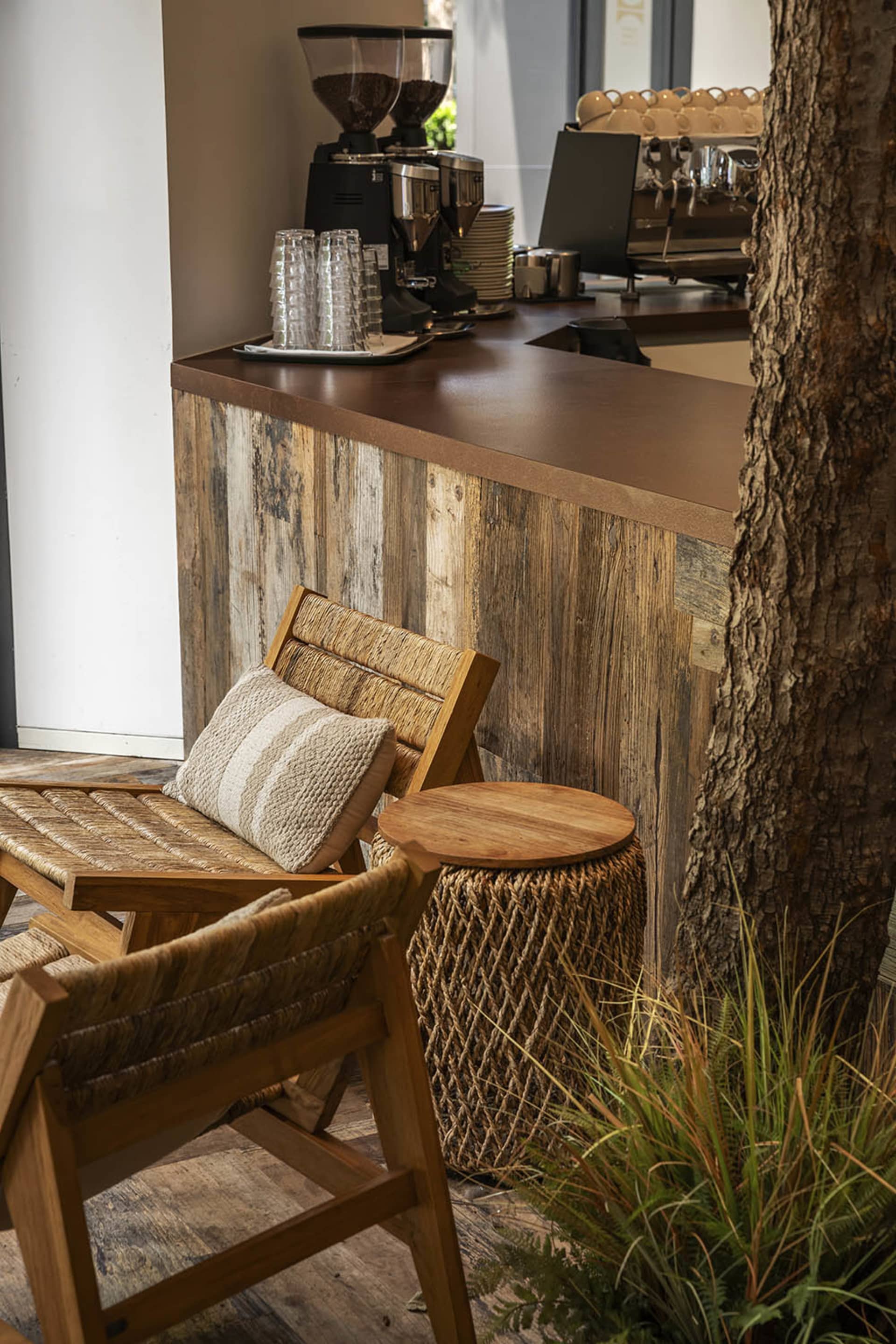 A rustic bar area with a wooden countertop and two chairs, surrounded by cups and a warm atmosphere