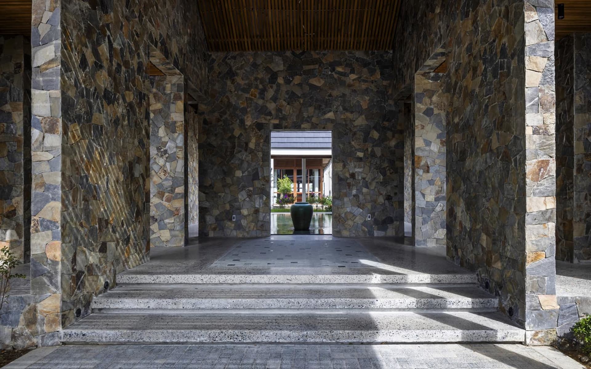 An open space with stone walls and steps leading upwards, featuring two sets of stairs and a calm atmosphere
