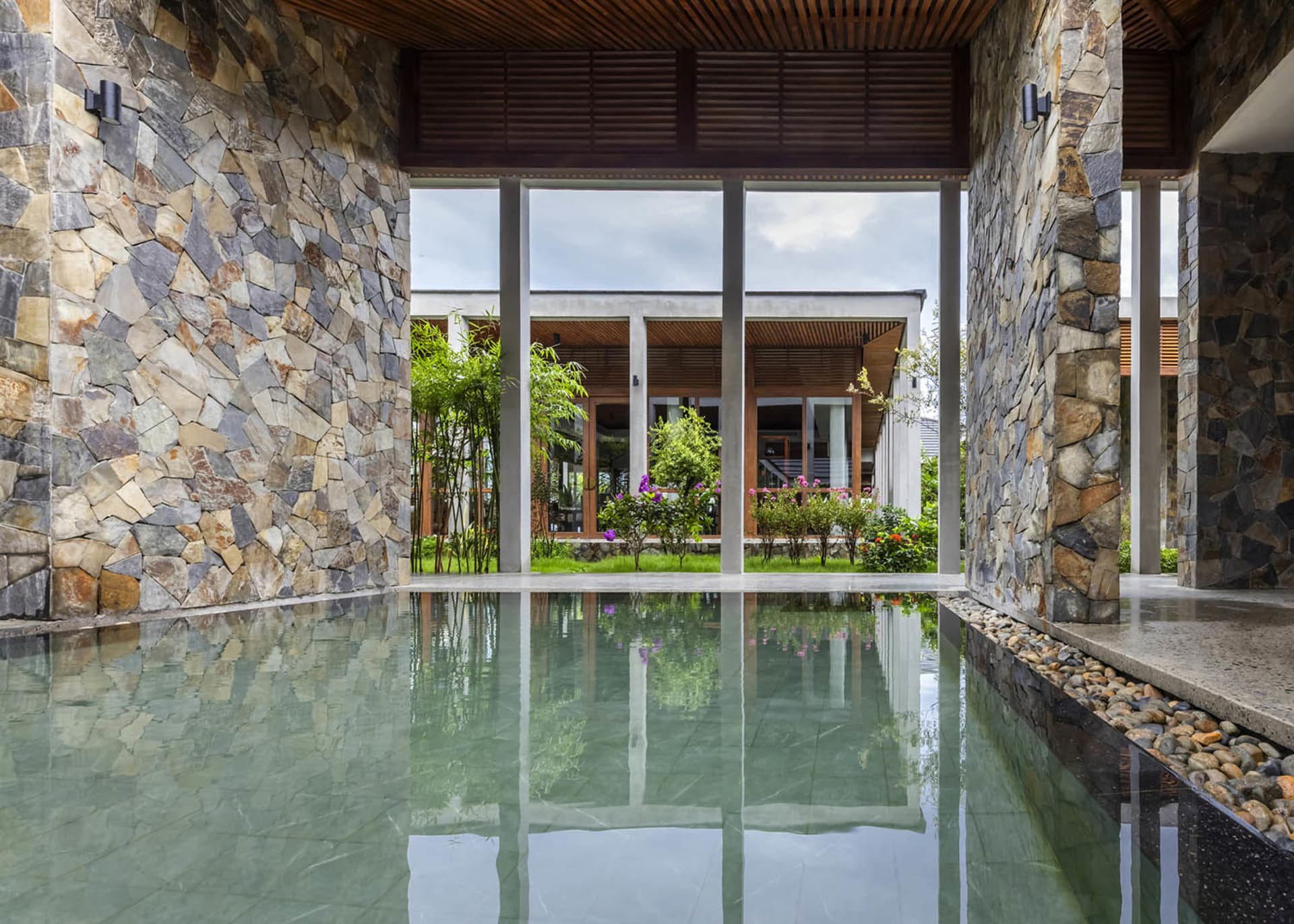 A well-lit pool area with a reflective surface, surrounded by potted plants and a serene ambiance