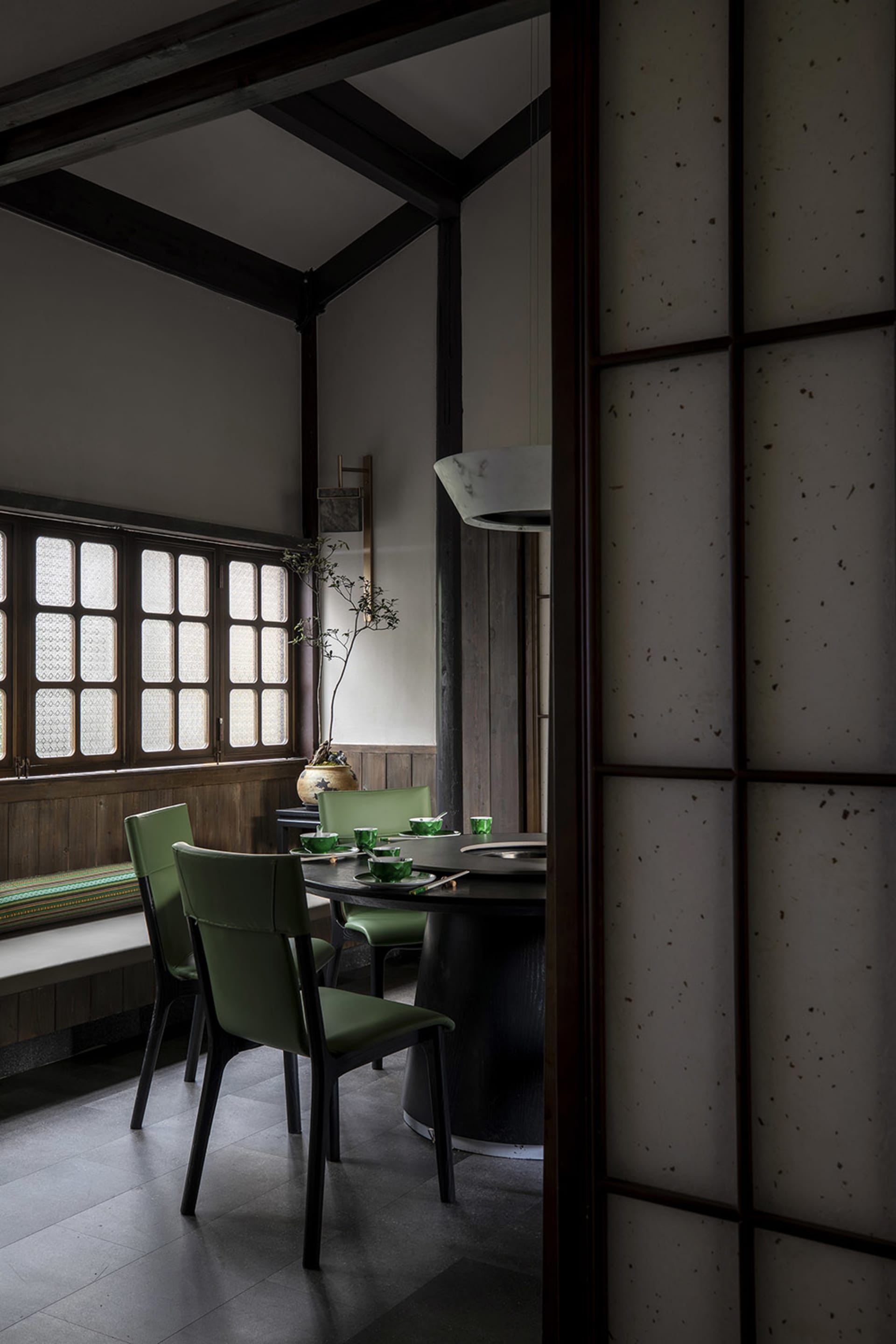 A calm and inviting dining area with a wooden table and chairs, set with cups and a vase, surrounded by a larger living space