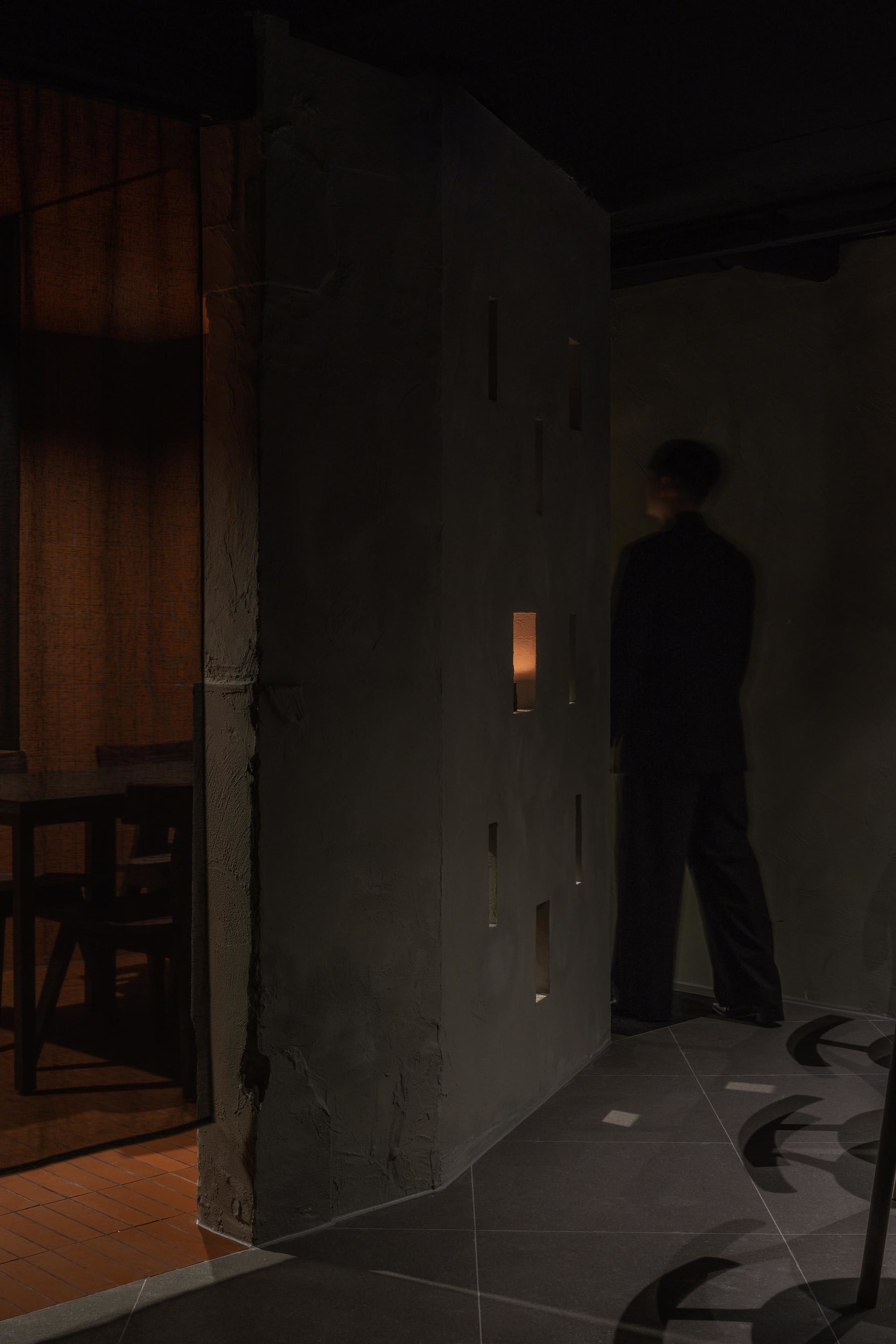 A man in a suit stands in front of a doorway in a room with two chairs, creating an elegant and sophisticated atmosphere