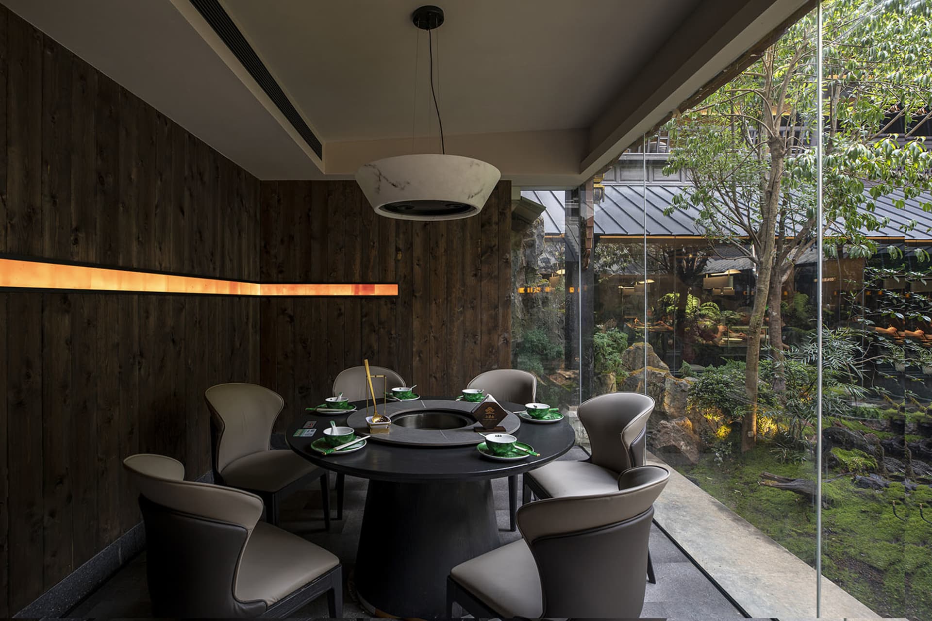 A modern dining area with a round table set for a meal, surrounded by chairs, green plates, and cups, in a space that invites socializing and comfort