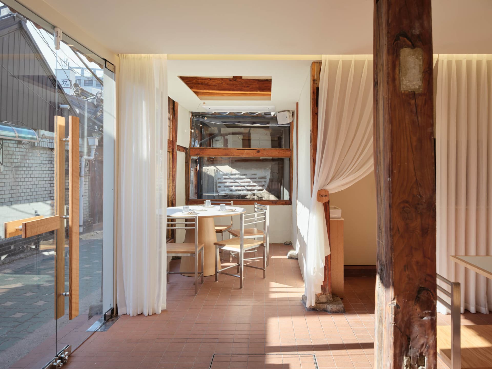Warm and inviting dining space with wooden elements, two tables, and chairs, creating a rustic atmosphere