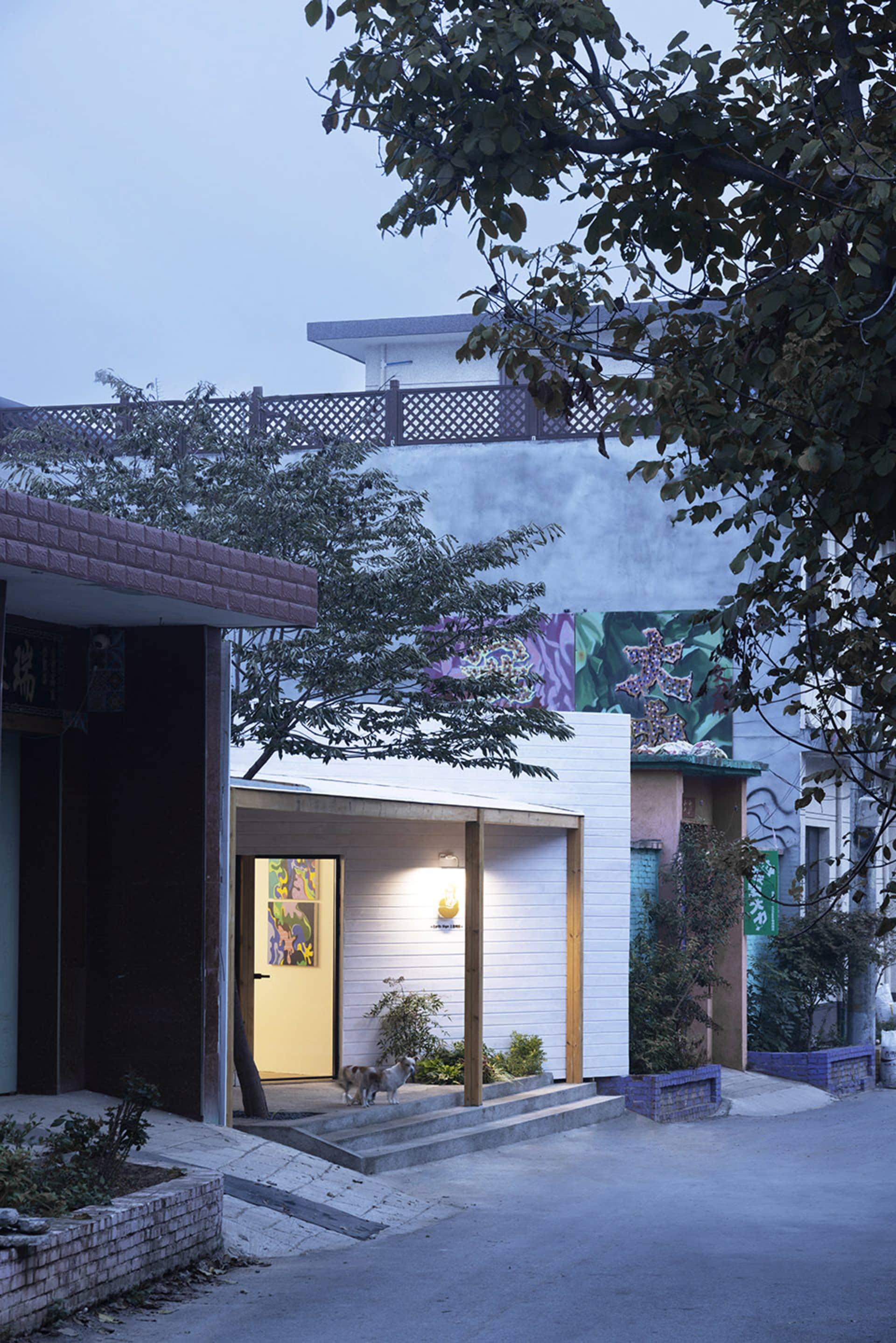 A modern house with a white exterior, a balcony, and trees visible in the background