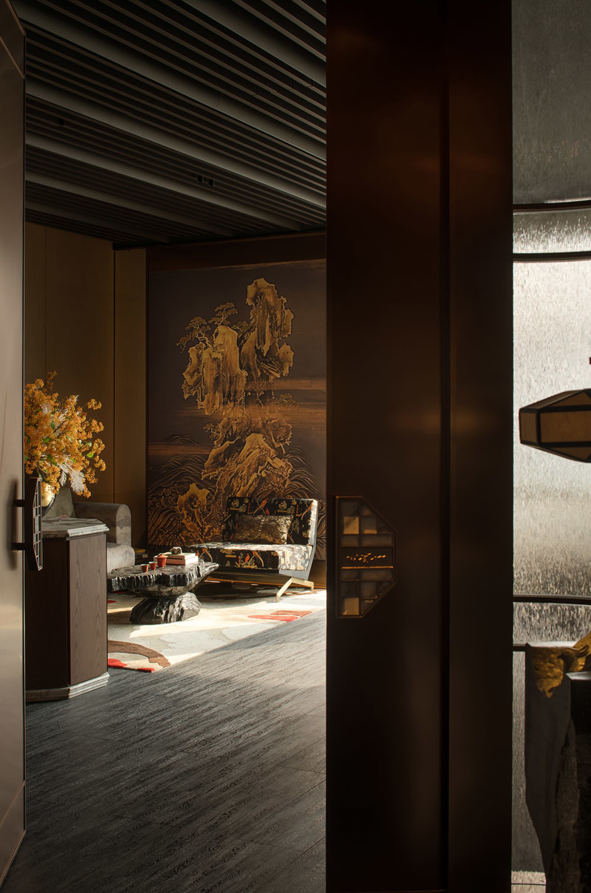 A warm and inviting Asian-inspired living area with a large wooden doorway, two couches, a chair, and a vase, creating a comfortable and relaxing space