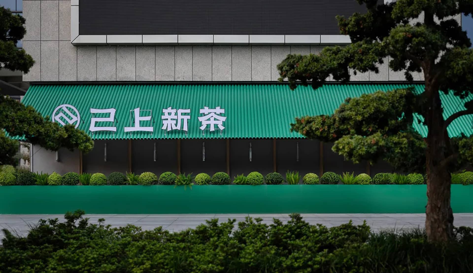 一座帶有綠色屋頂與盆栽的混凝土建築，位於都市環境中，強調永續性