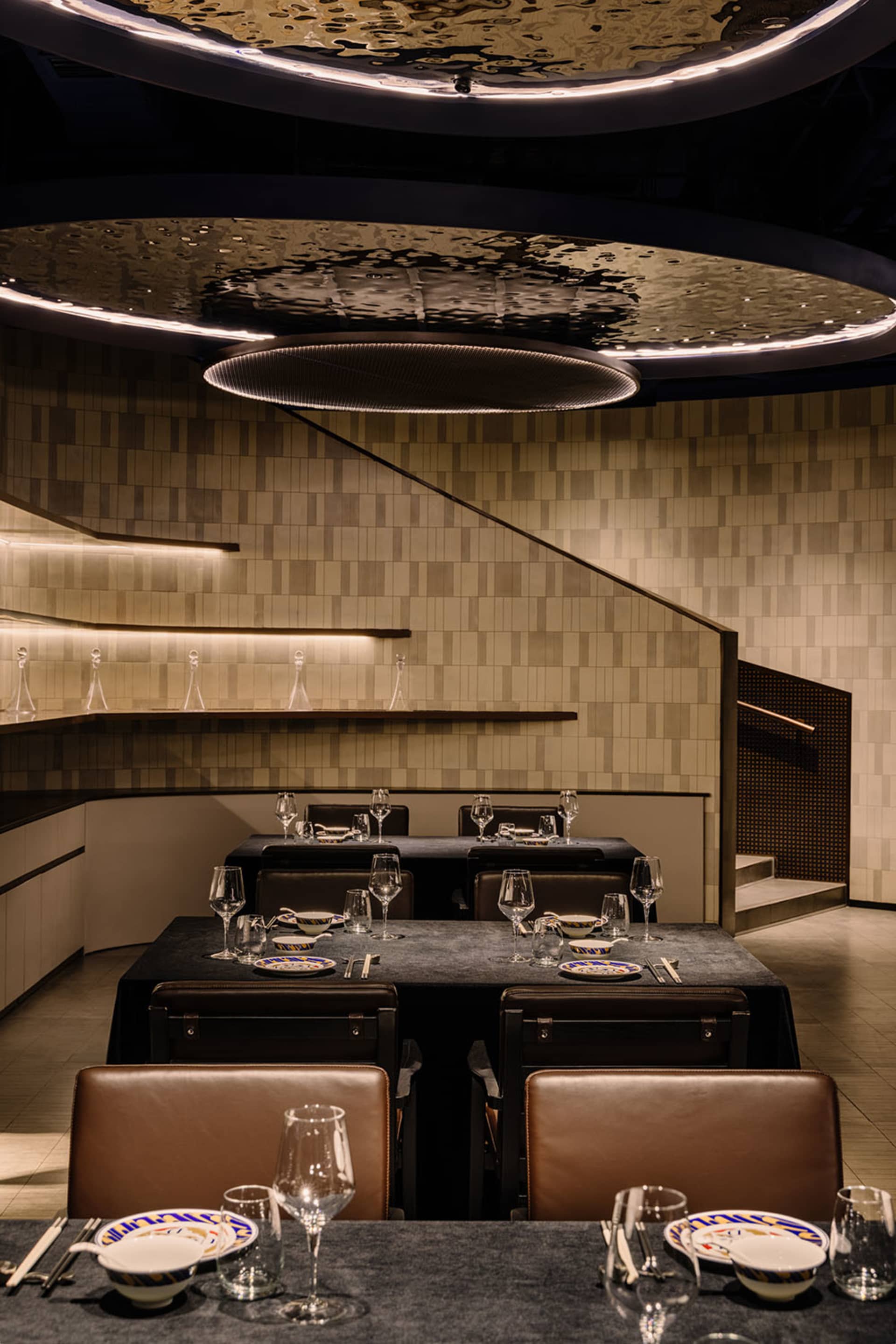 Elegant dining area with a round table, chairs, wine glasses, plates, and utensils, creating a sophisticated ambiance