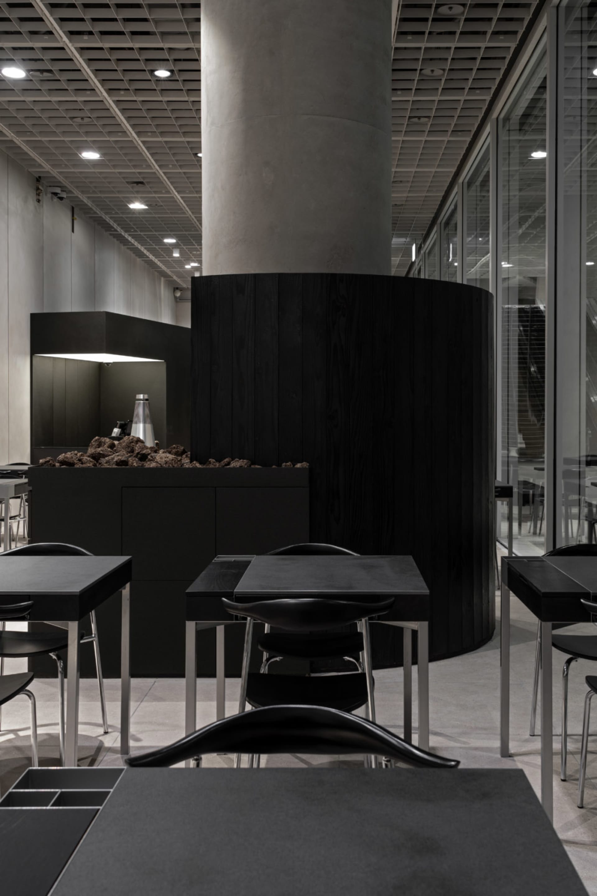A modern restaurant interior with black tables and chairs, multiple dining tables and chairs in a stylish and inviting space